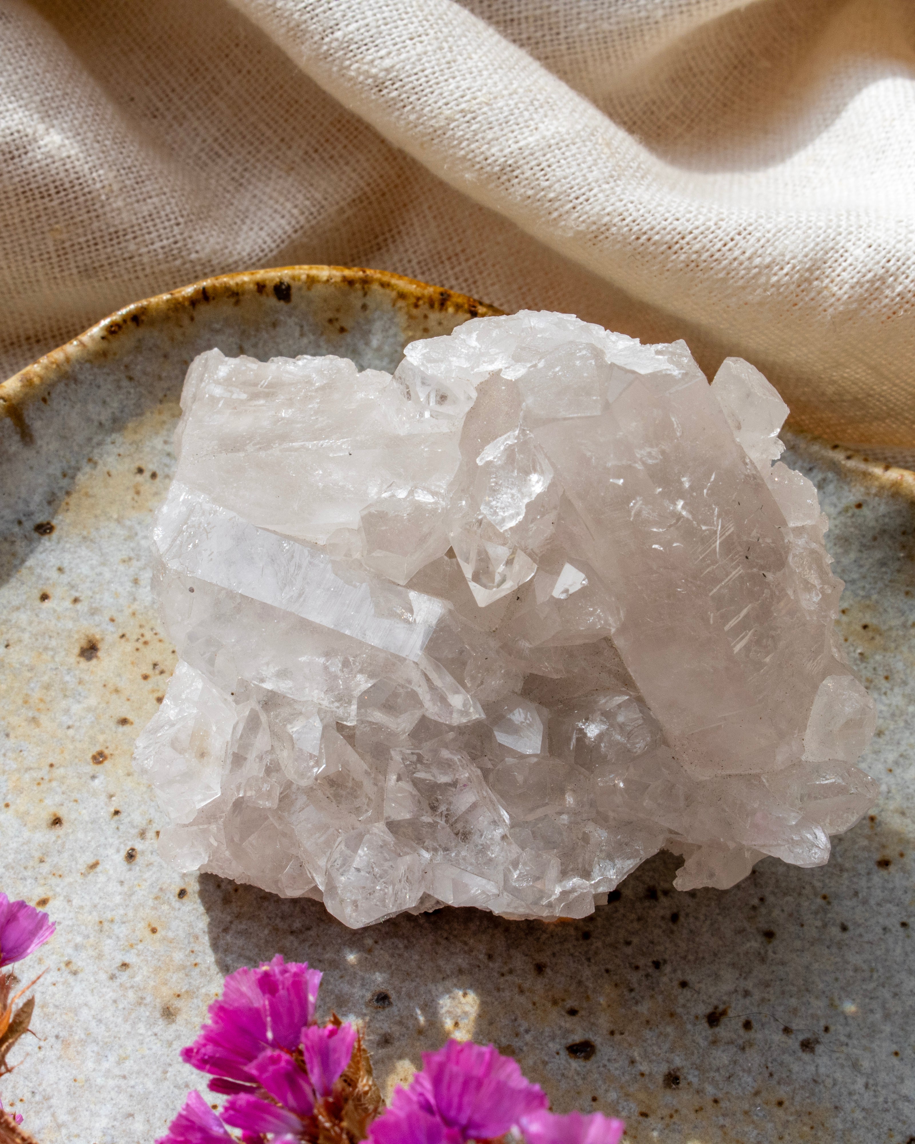 Crystal rock on a textured surface with pink flowers