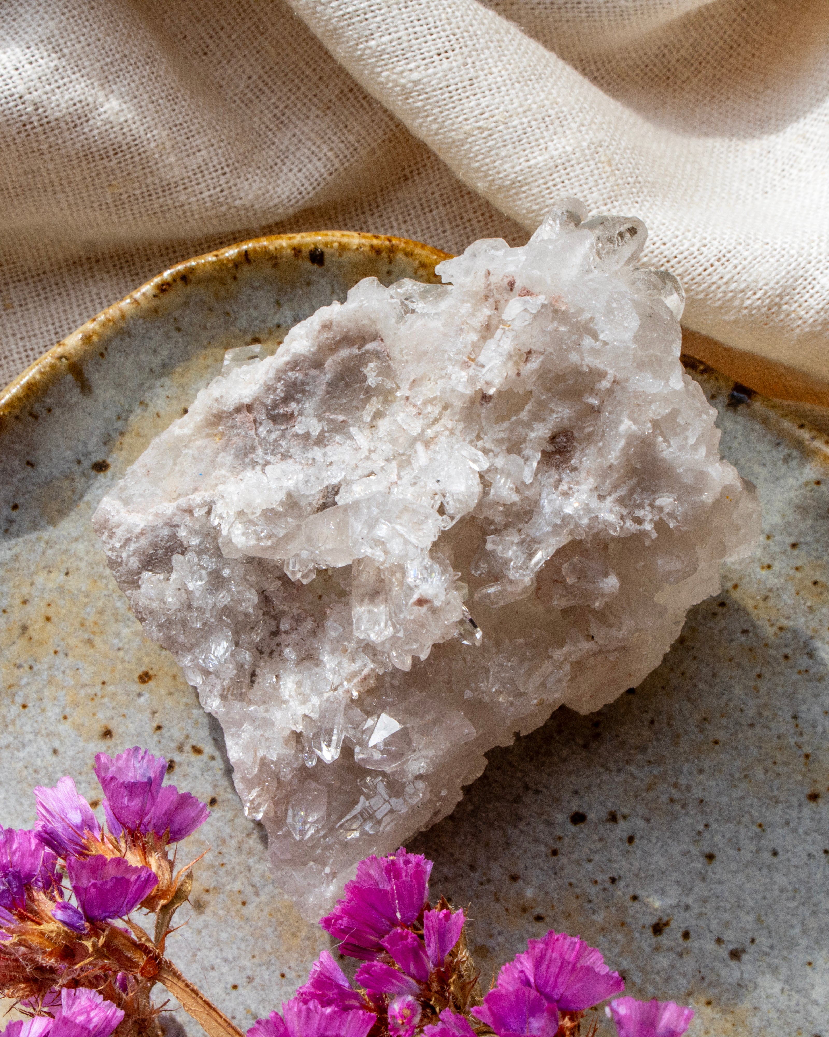 Crystal rock on a textured surface with purple flowers