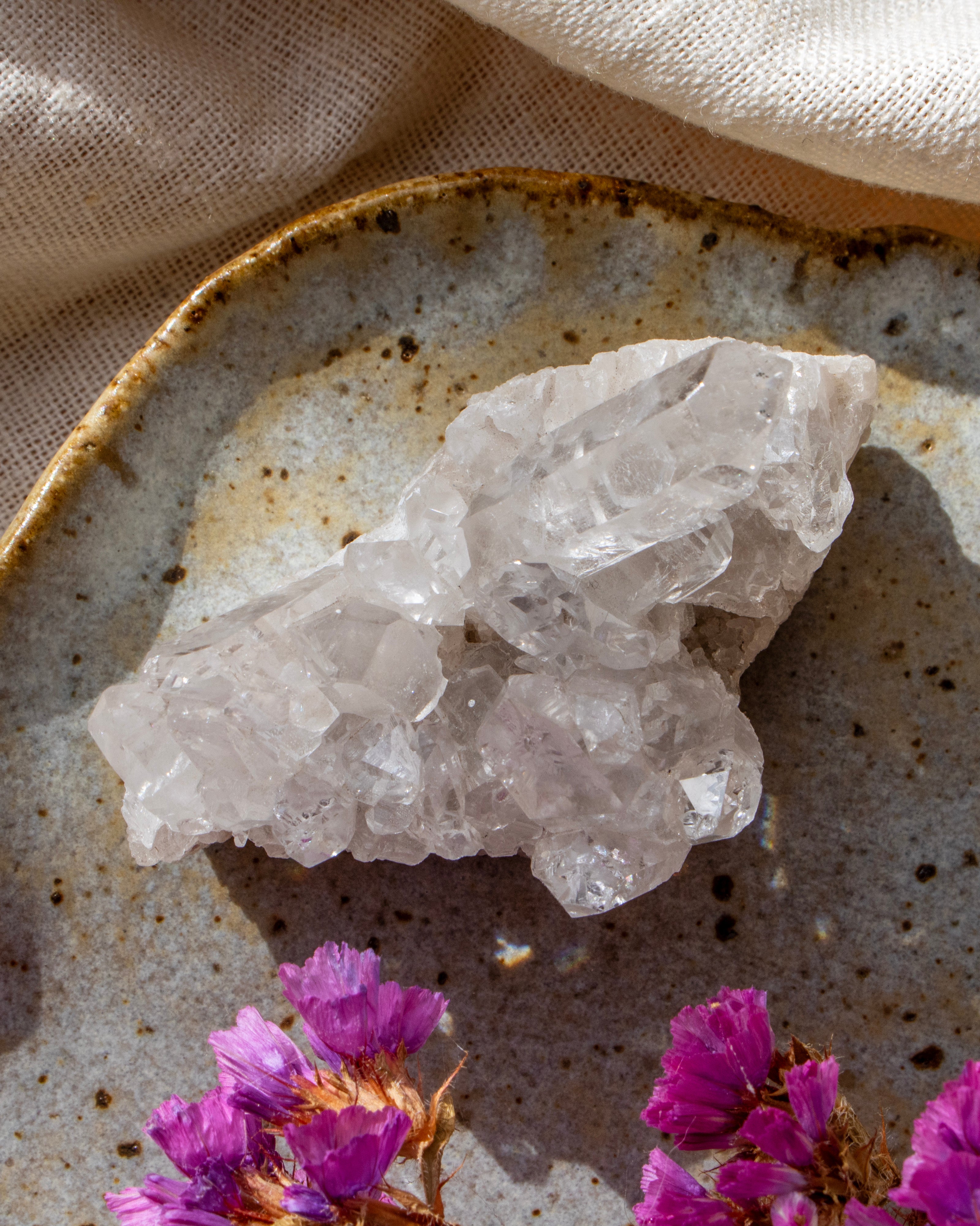 Crystal rock on a textured surface with pink flowers