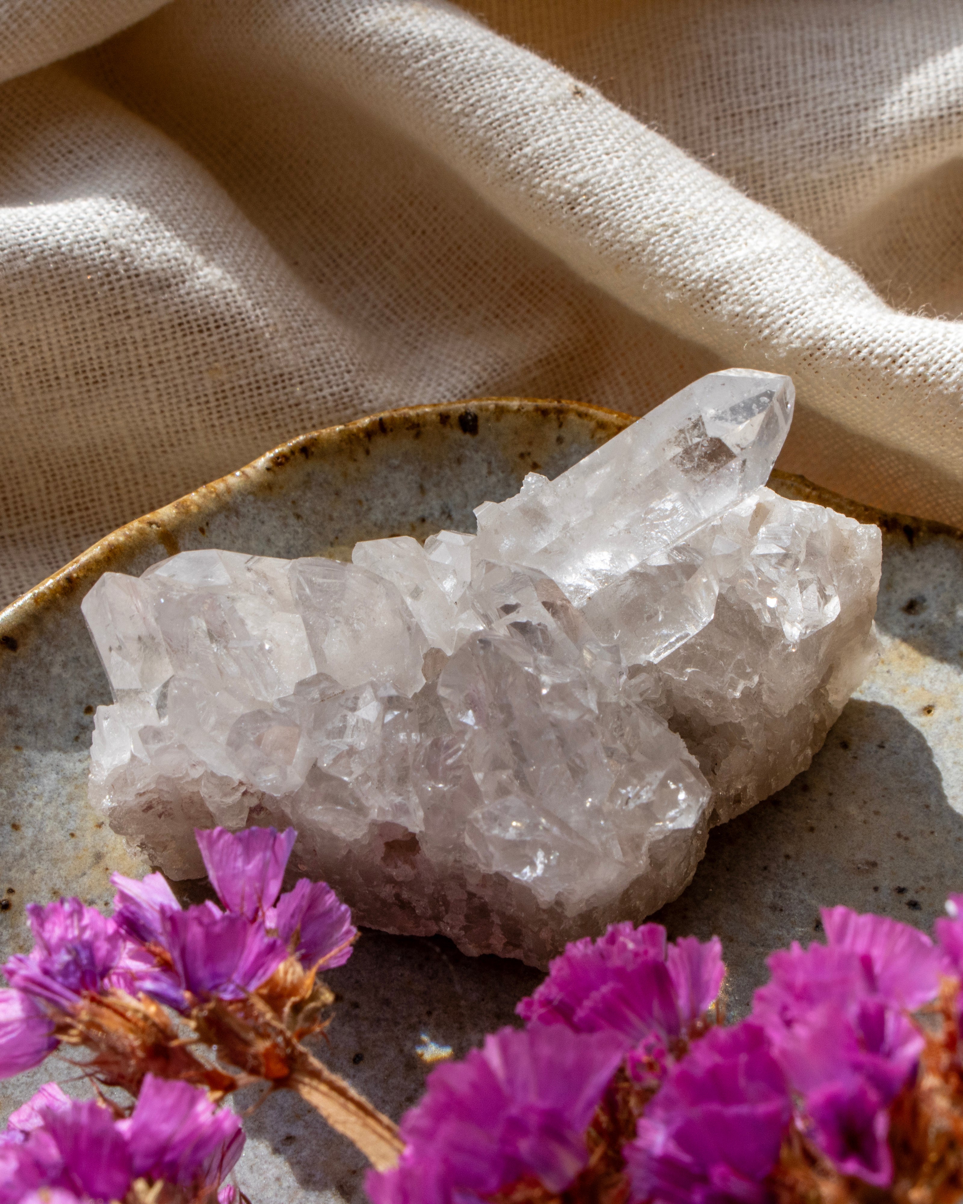 Crystal cluster on a textured surface with purple flowers