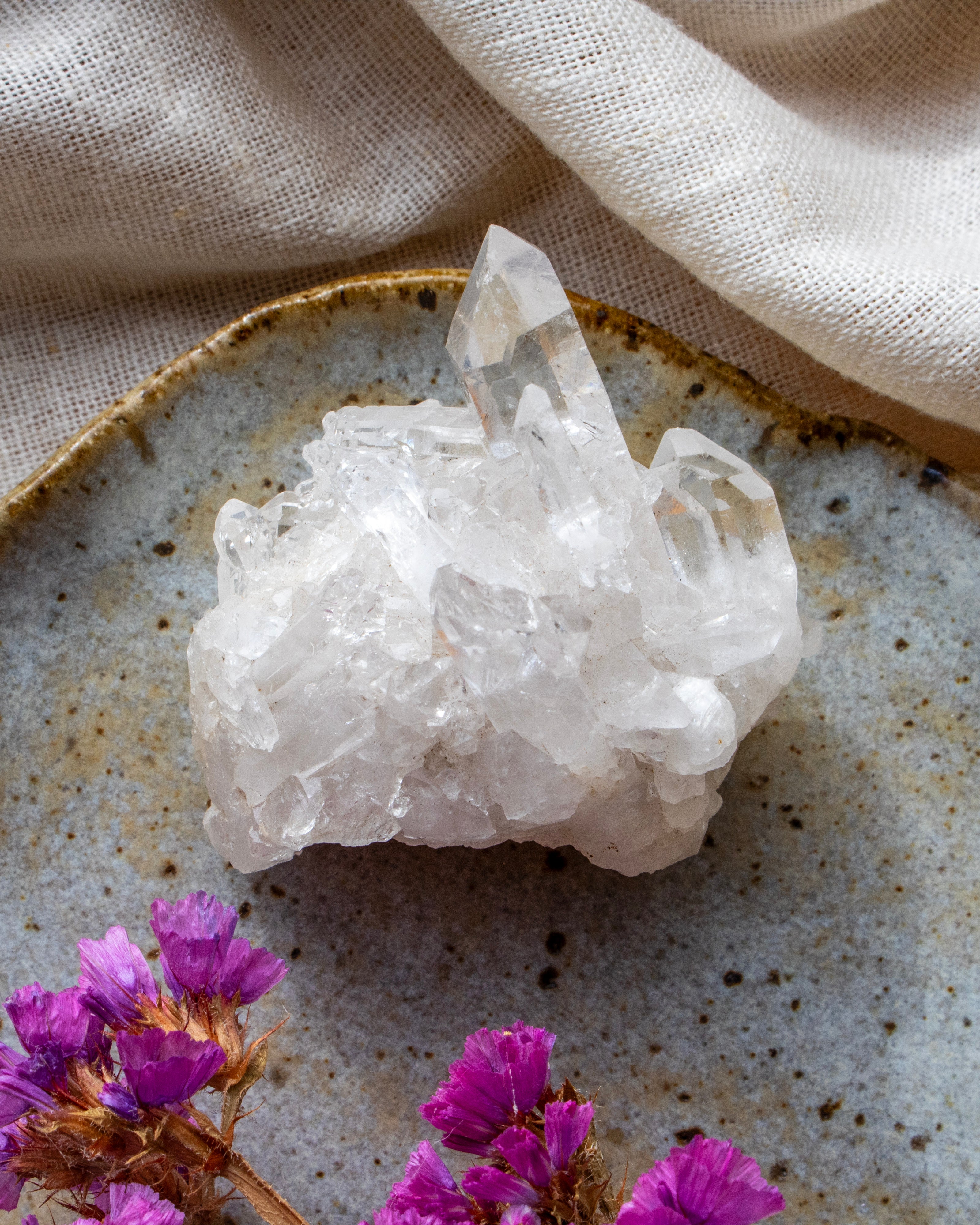 Crystal cluster on a textured surface with purple flowers