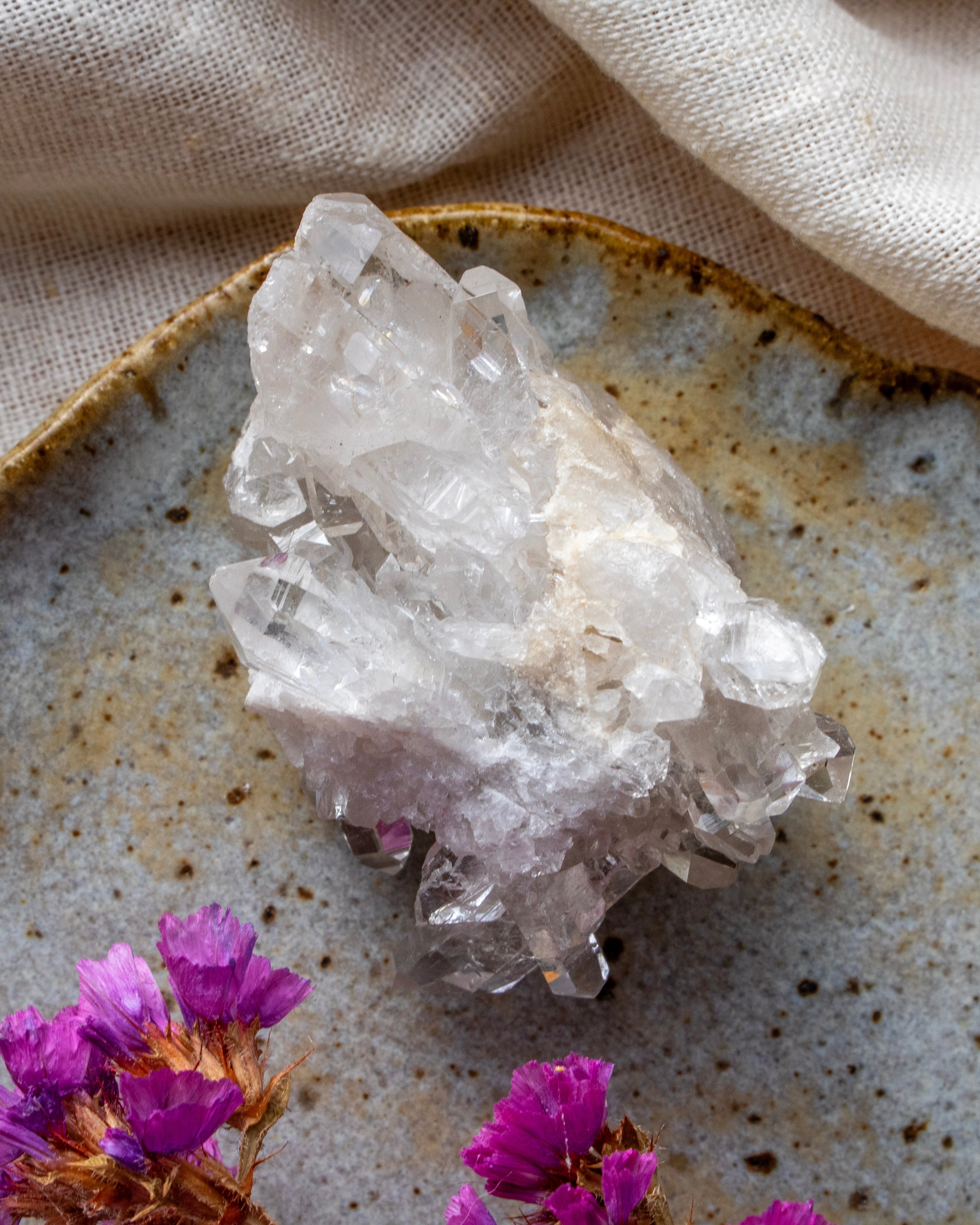 Crystal cluster on a textured surface with purple flowers