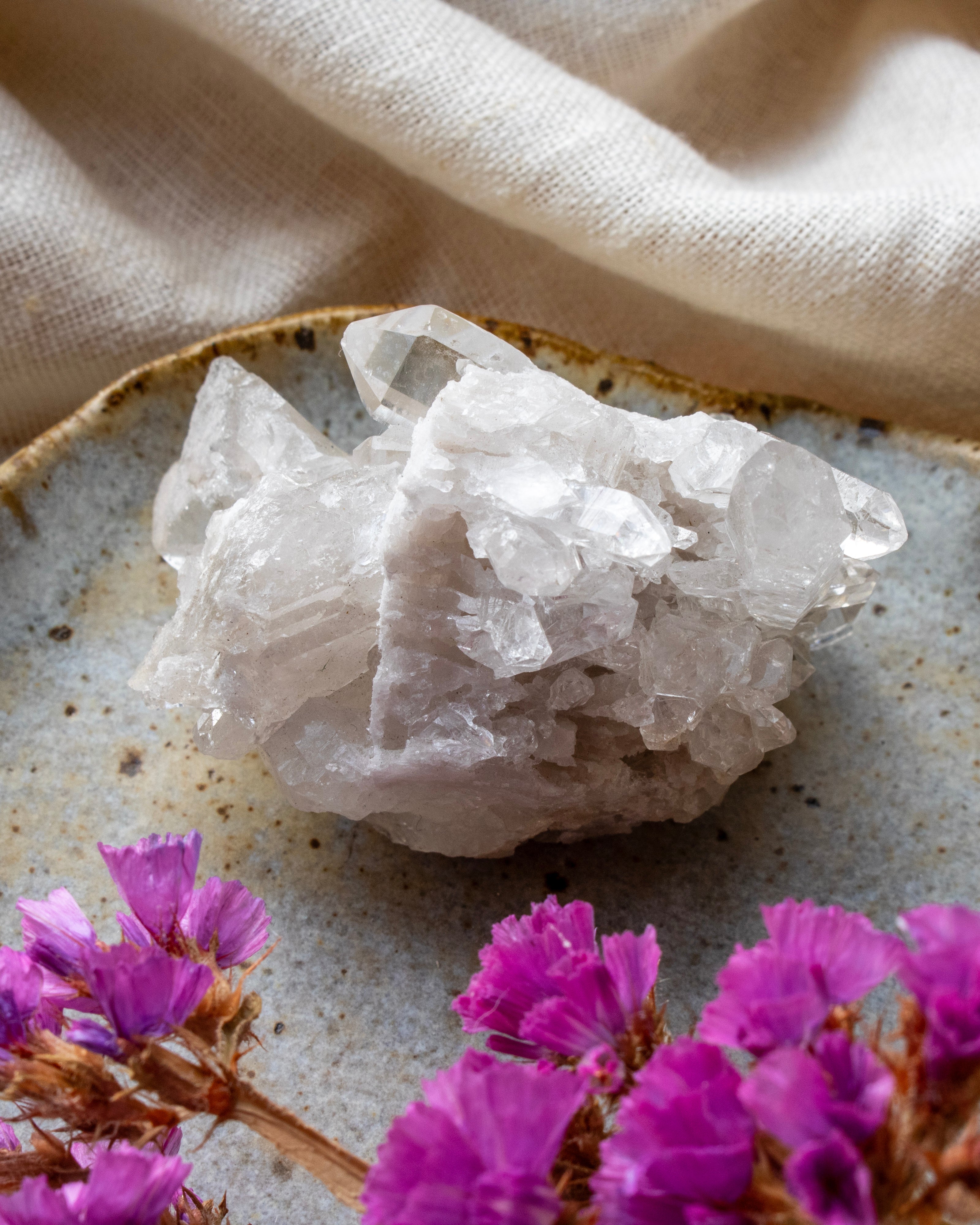 Crystal rock on a textured surface with pink flowers