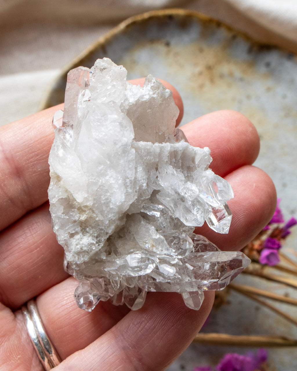 Hand holding a clear crystal rock with a blurred natural background