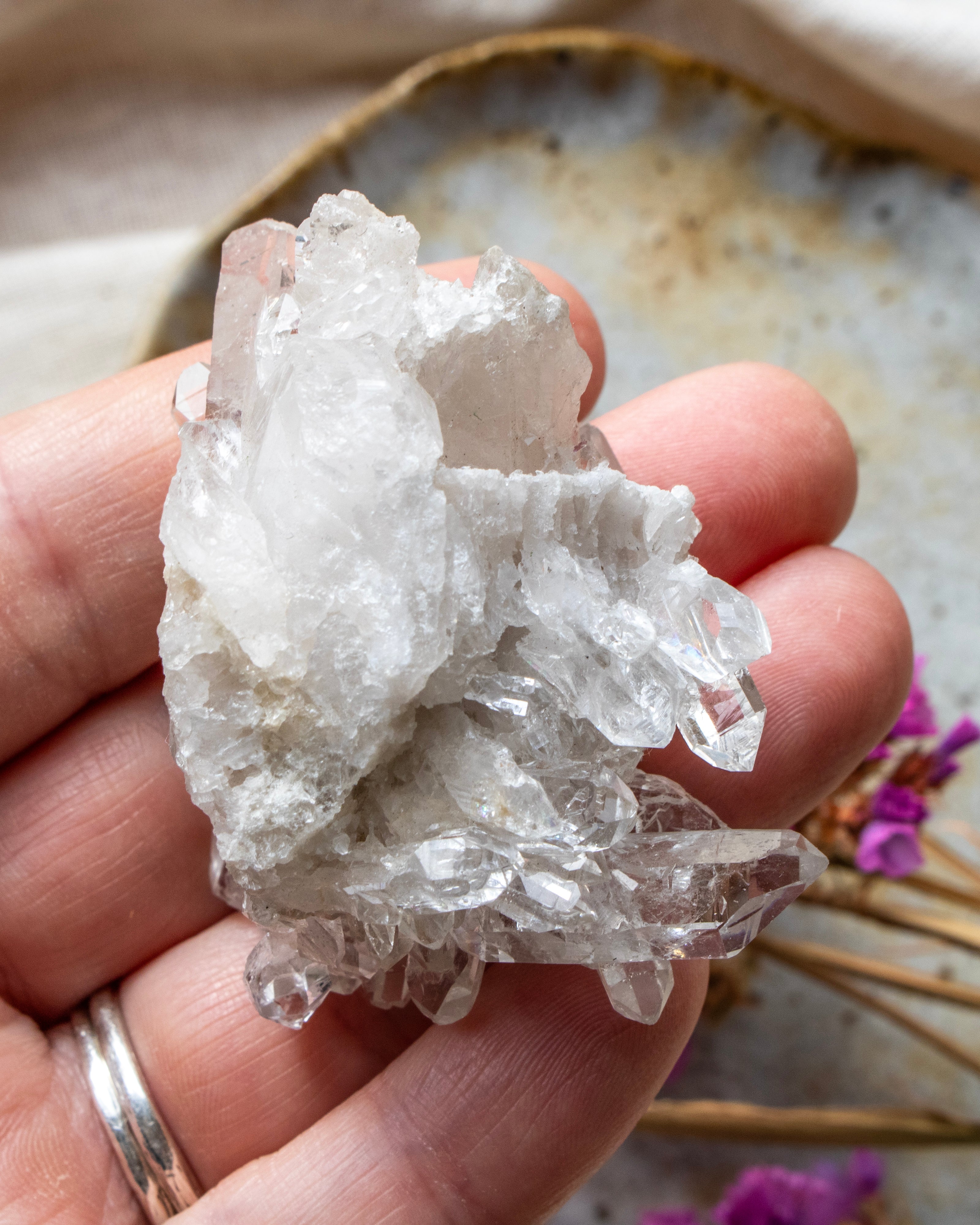 Hand holding a clear crystal rock with a blurred natural background
