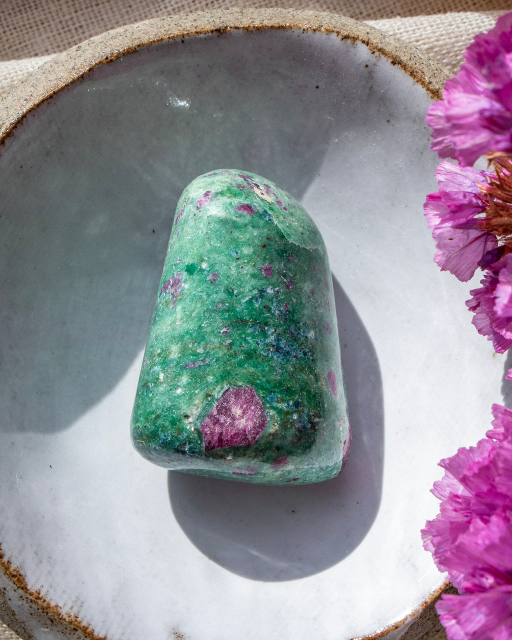 a green and purple stone in a ceramic dish with purple flowers