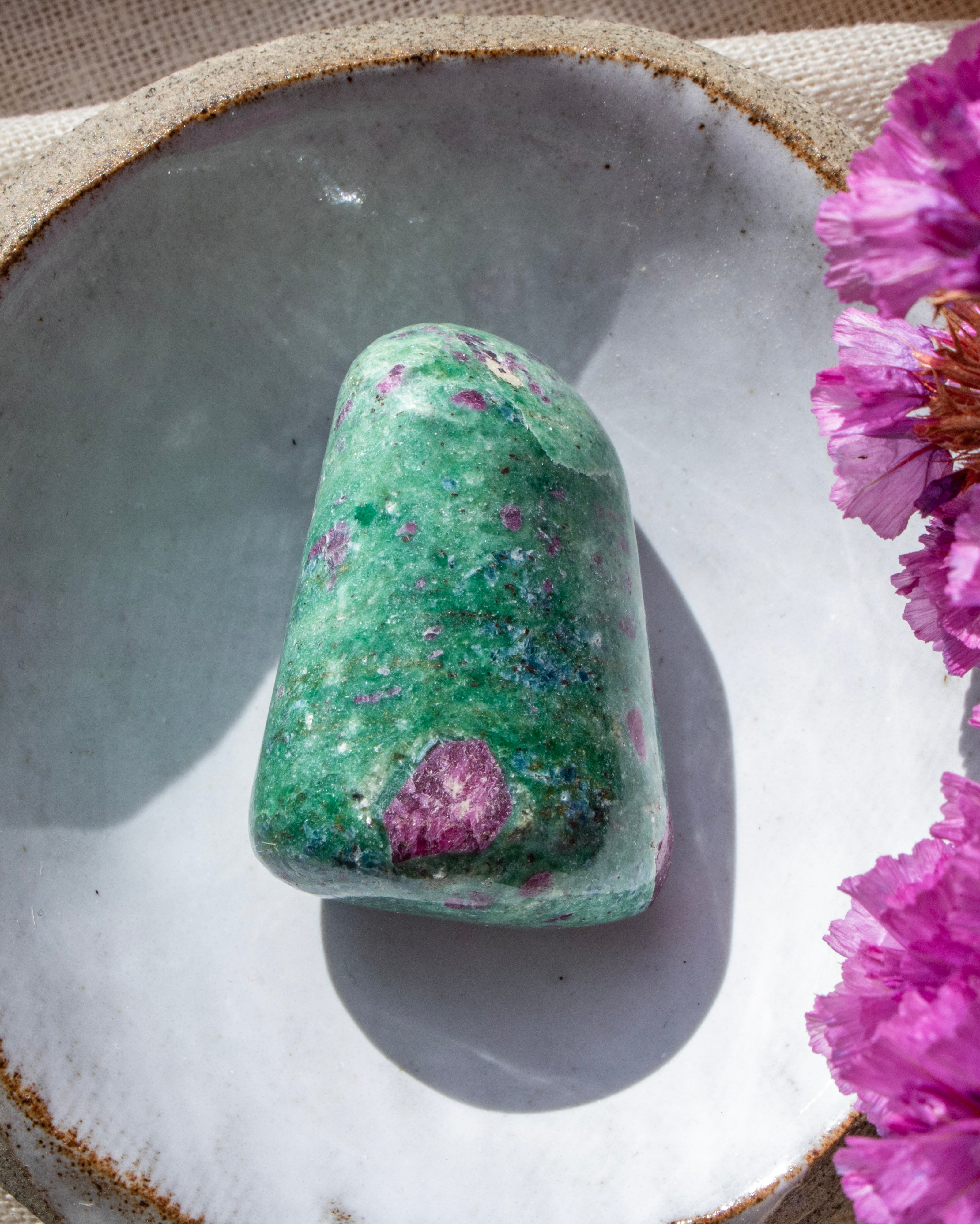 a green and purple stone in a ceramic dish with purple flowers