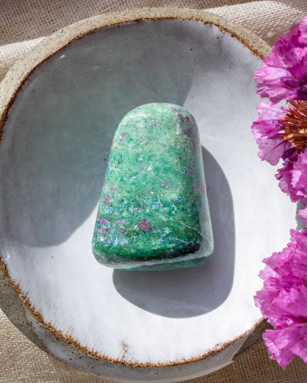 a green and purple stone in a ceramic dish with purple flowers