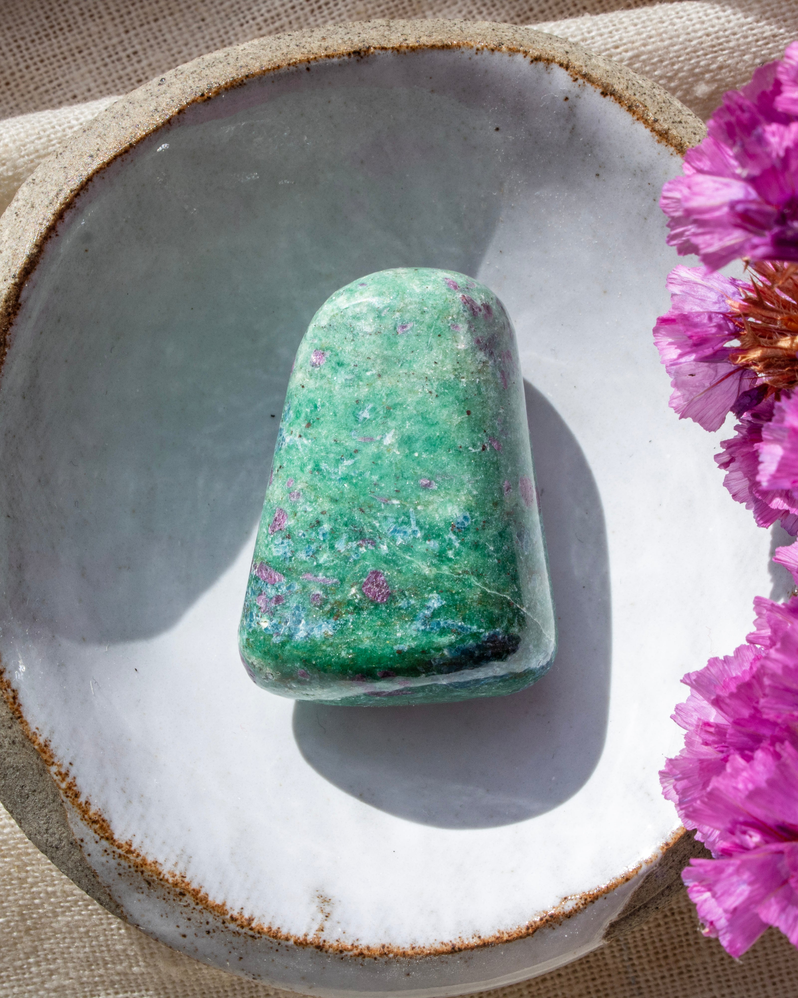 a green and purple stone in a ceramic dish with purple flowers