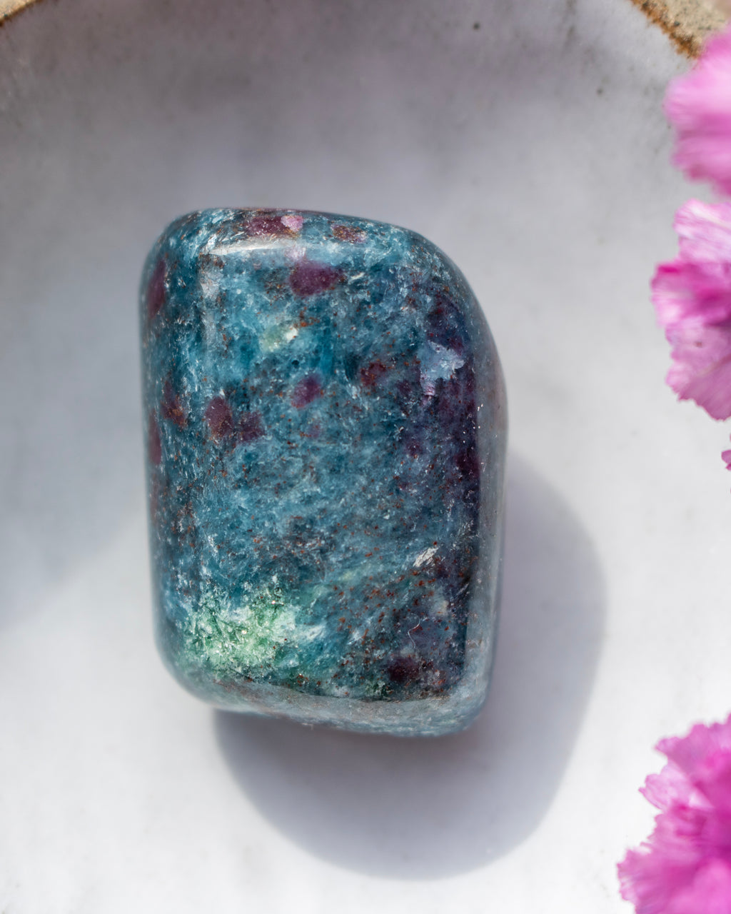 a dark blue and purple stone in a ceramic dish with purple flowers