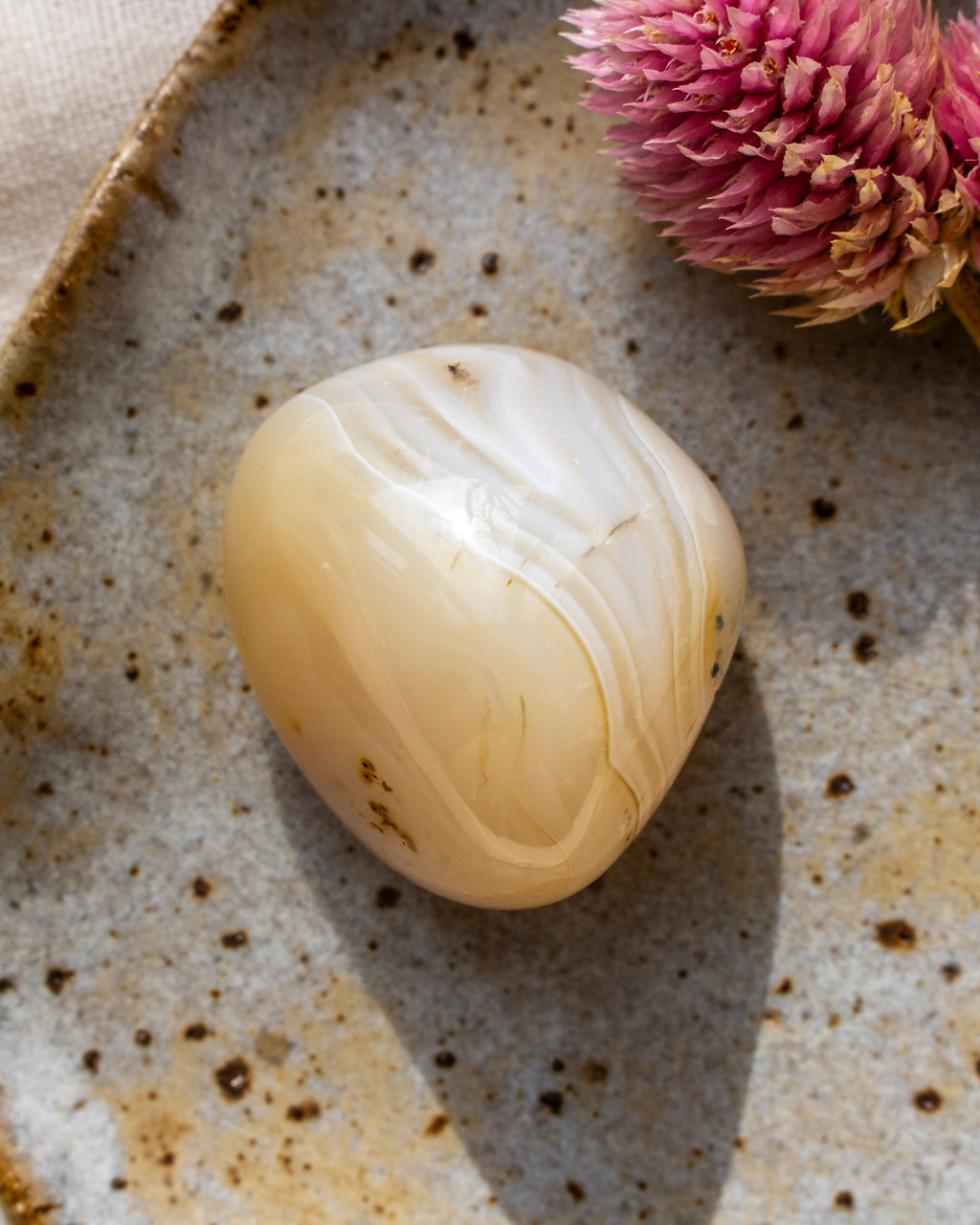 a beige pebble with banding on a brown ceramic dish