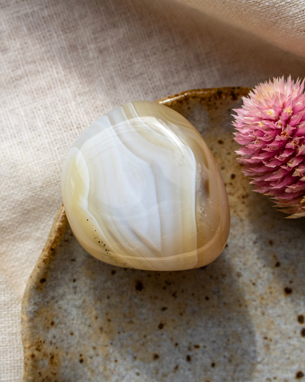 a beige pebble with banding on a brown ceramic dish
