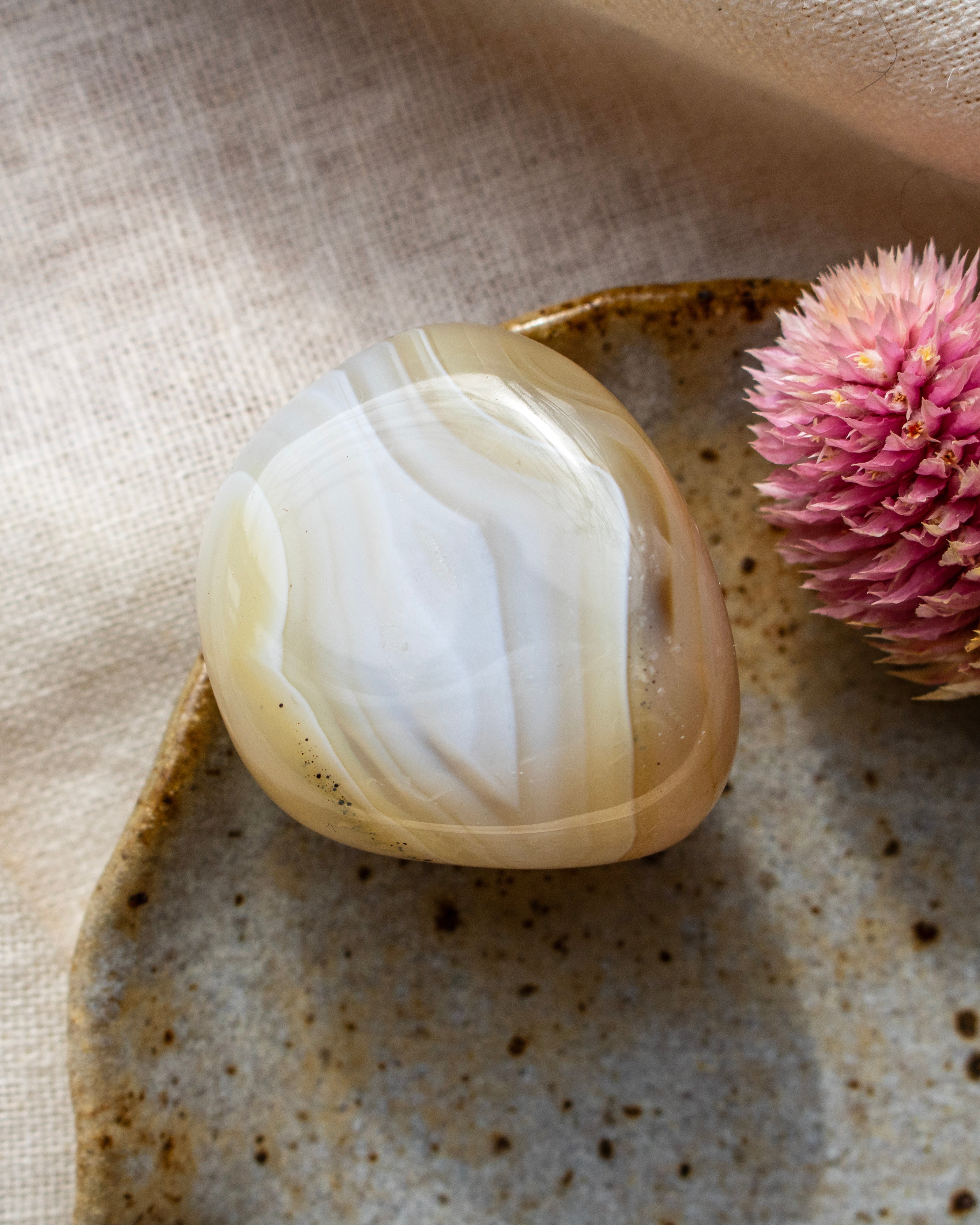 a beige pebble with banding on a brown ceramic dish