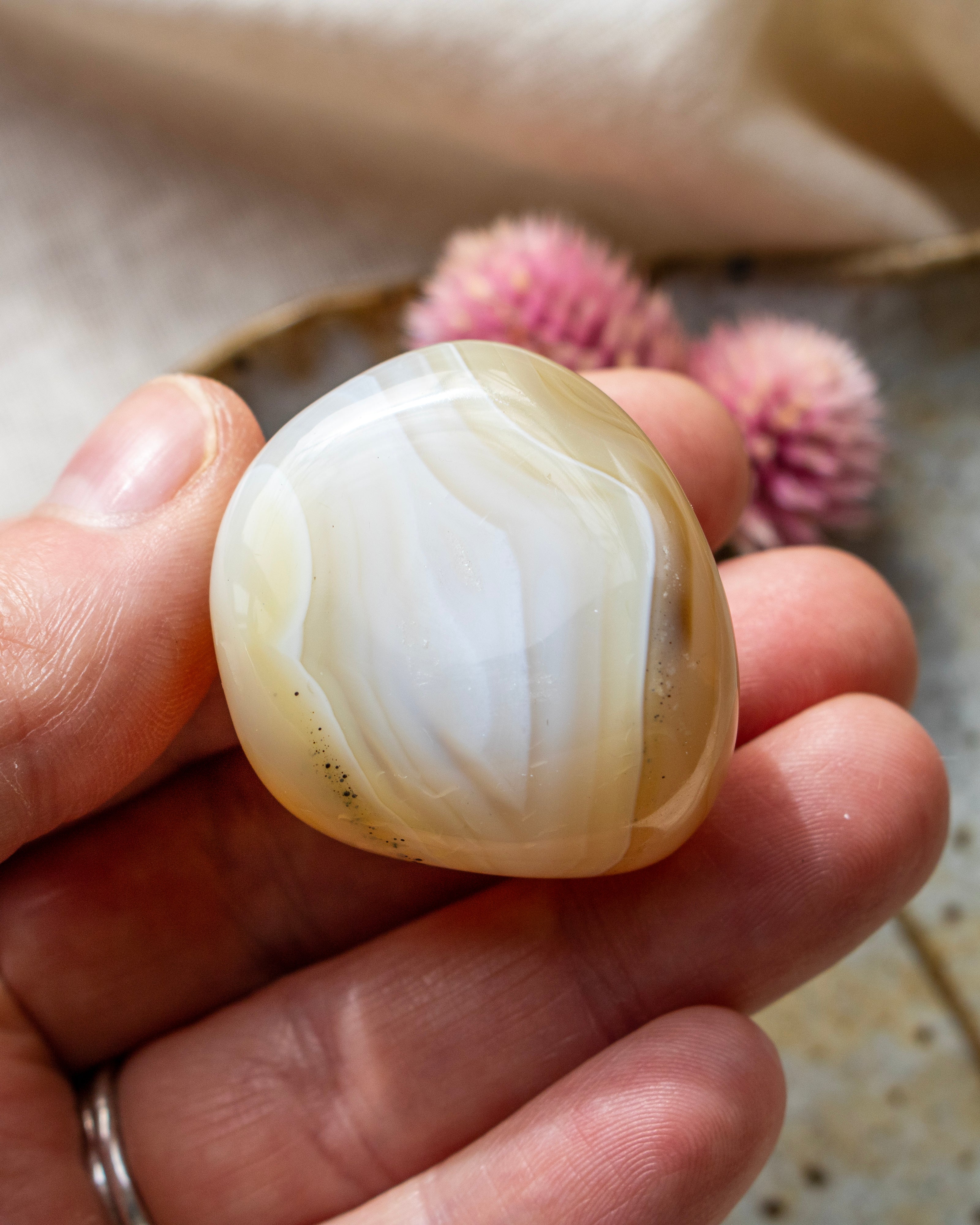 a yellowy beige pebble being held with fingers and a blurred background