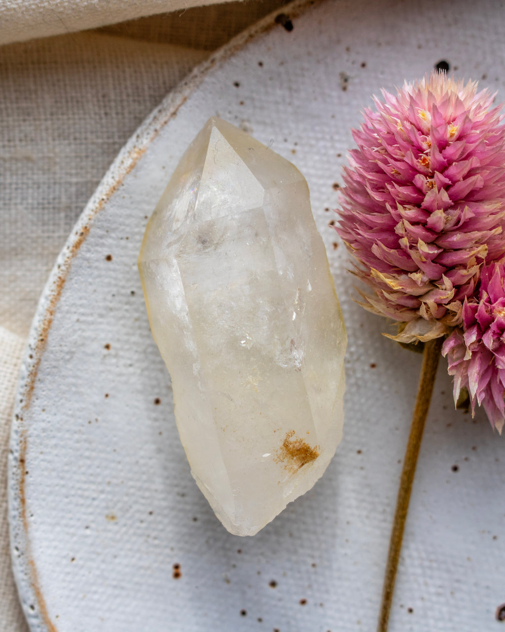 a quartz point on a white ceramic dish with a pink flower
