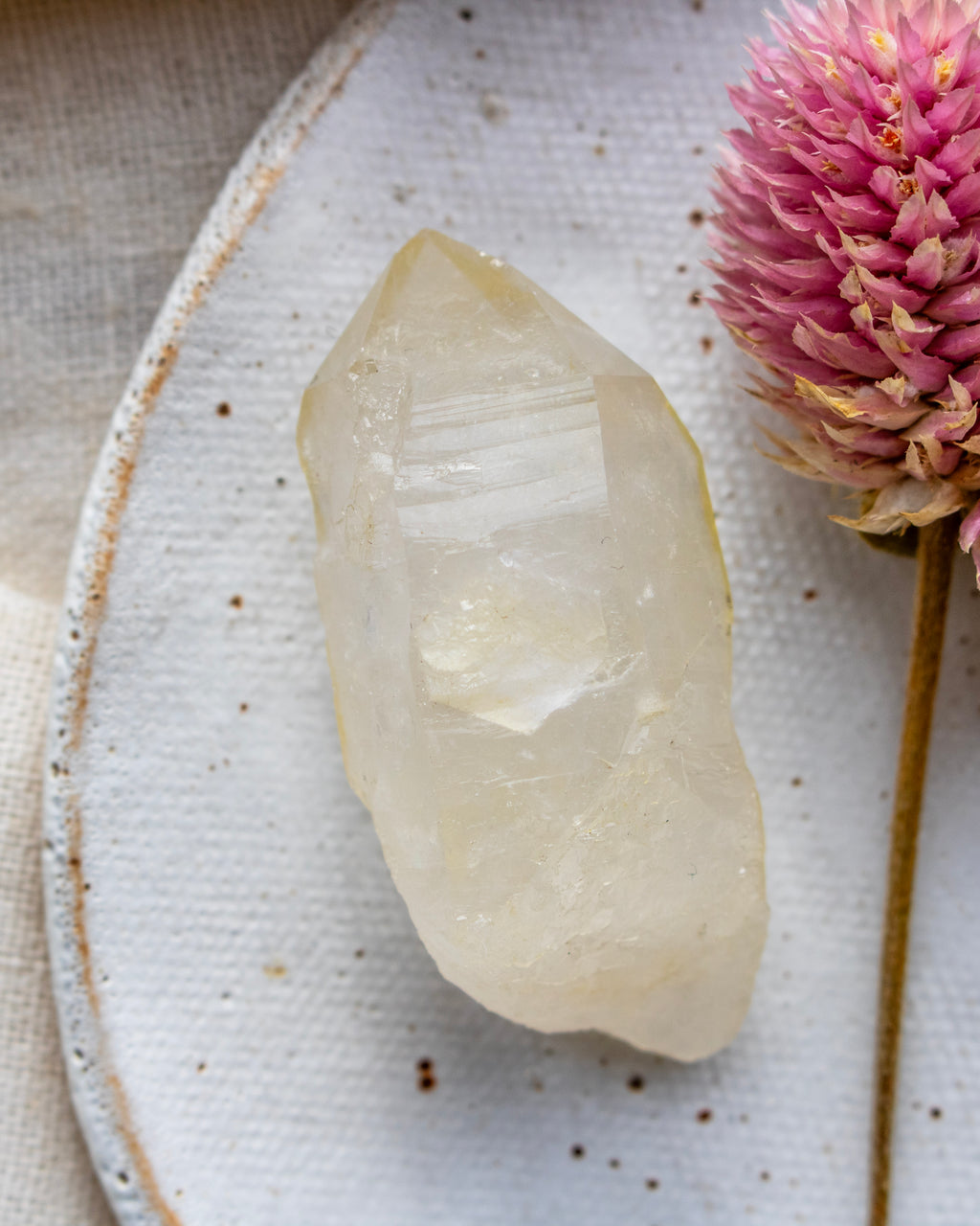 a quartz point on a white ceramic dish with a pink flower