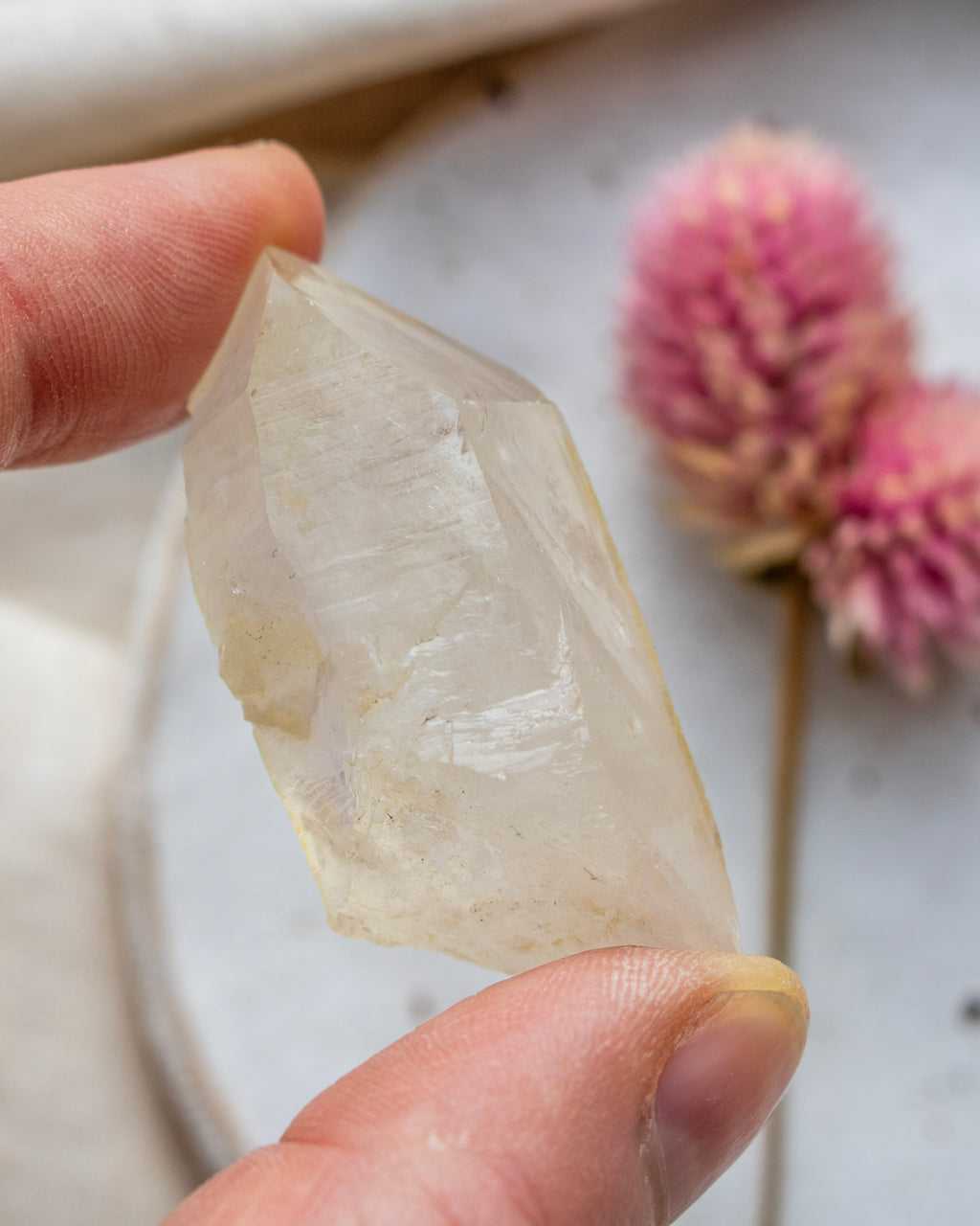 a quartz point being held with fingers and a blurred background