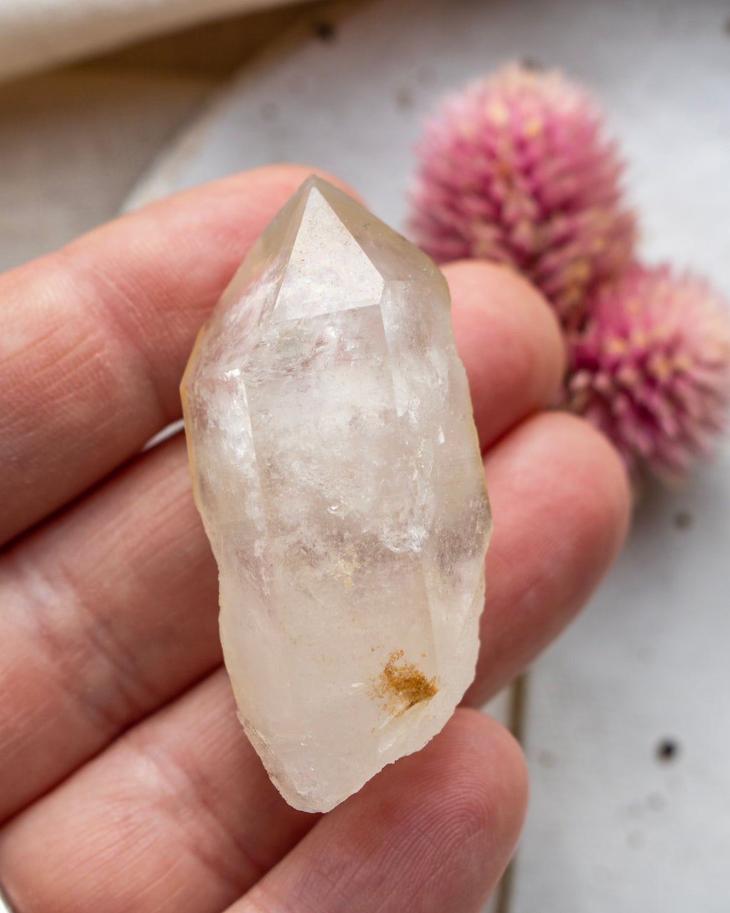a quartz point being held with fingers and a blurred background