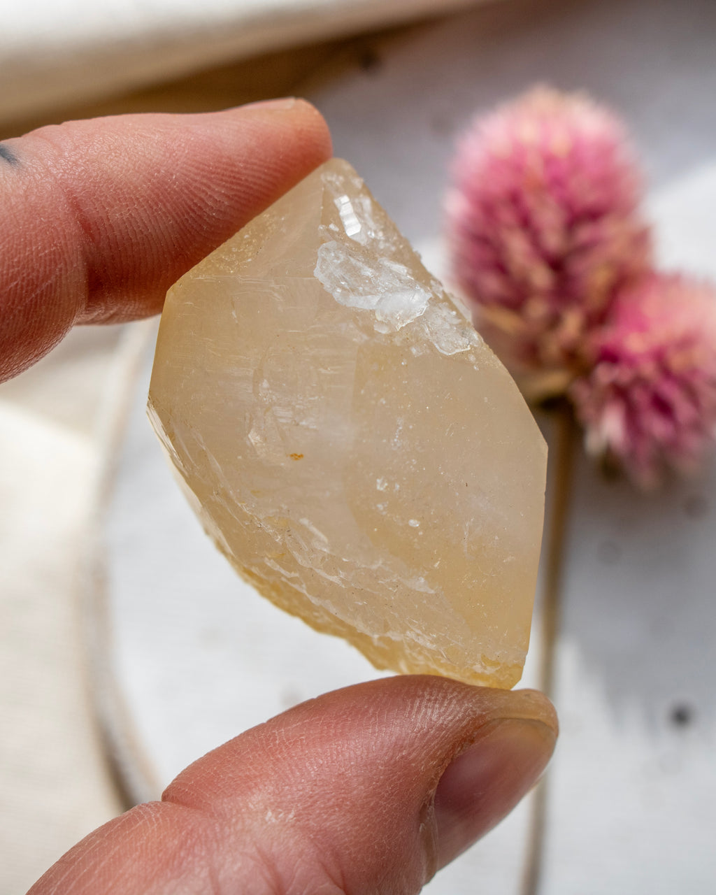 a yellow quartz point being held with fingers and a blurred background