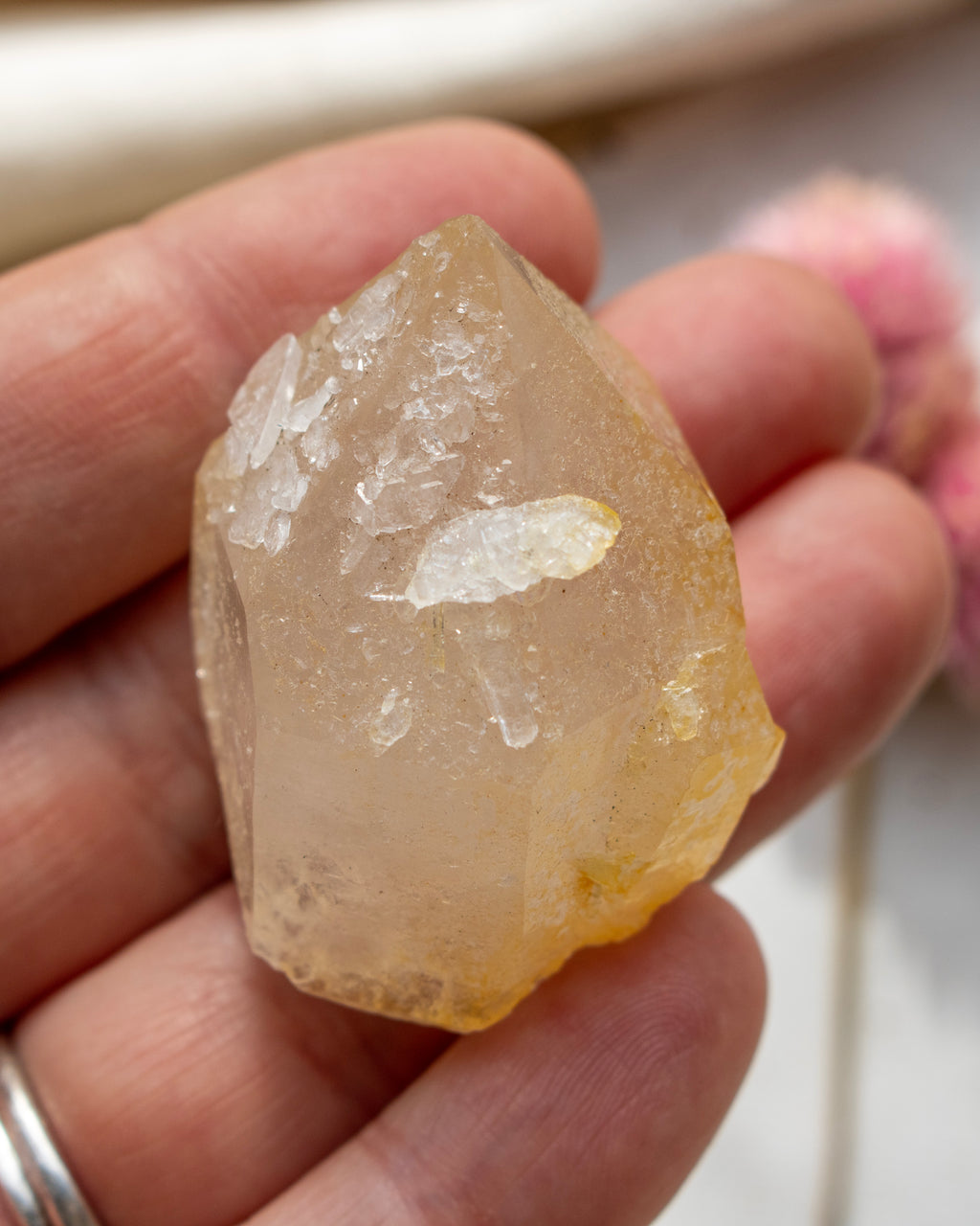 a yellow quartz point being held with fingers and a blurred background