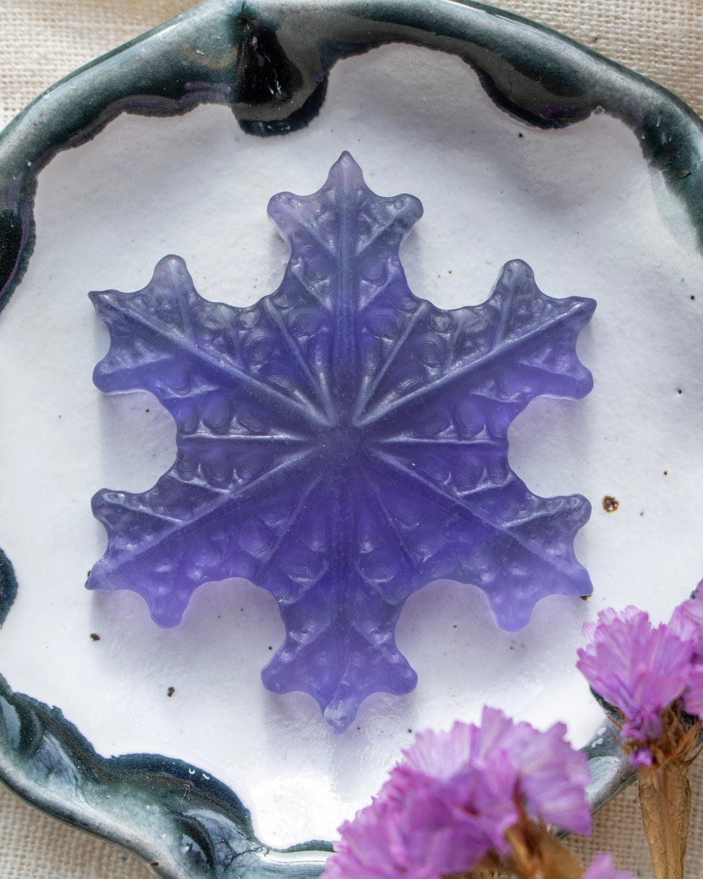 a purple snowflake in a white ceramic dish