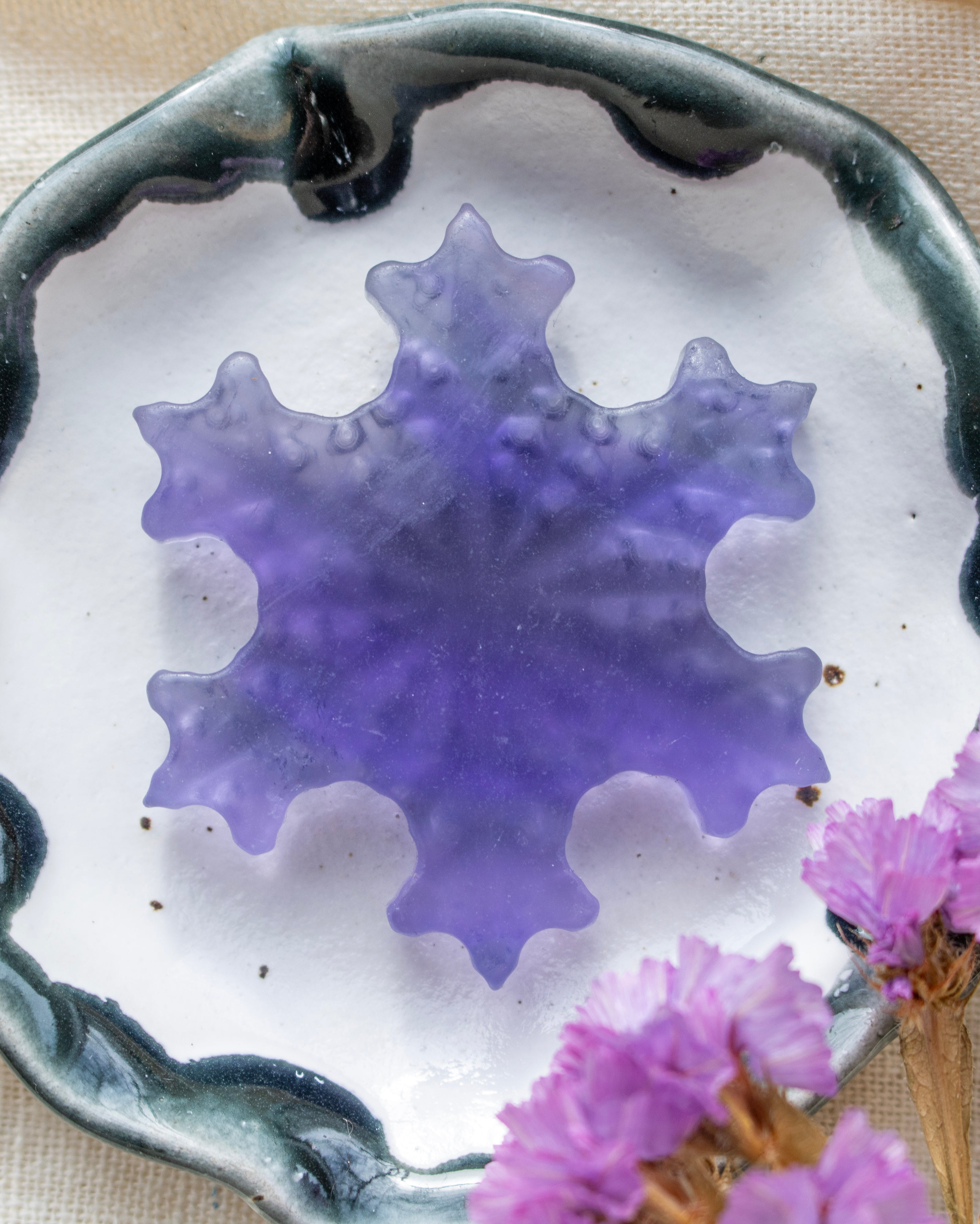 a purple snowflake in a white ceramic dish
