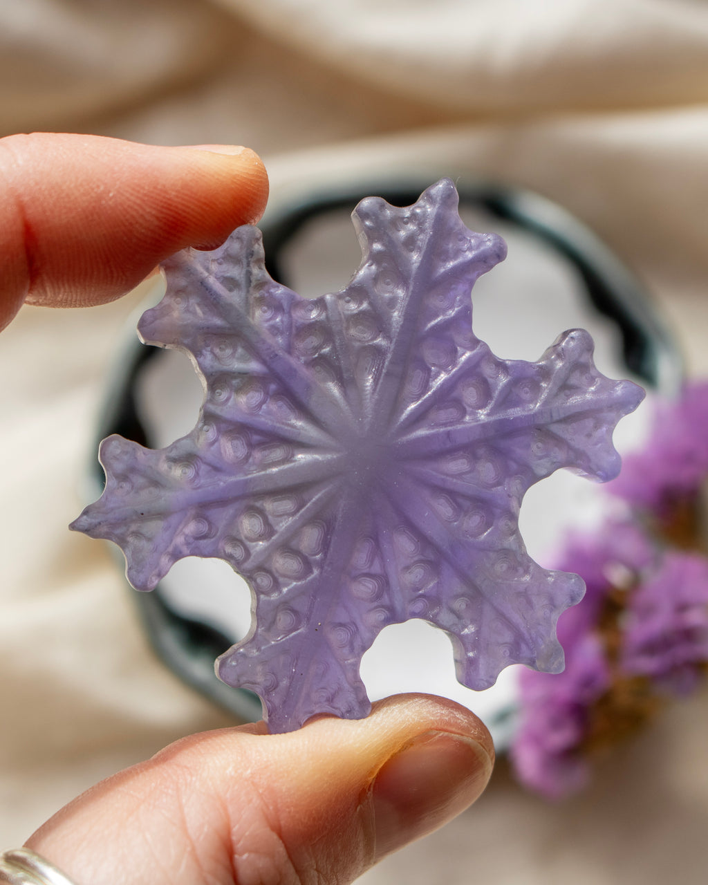 a purple snowflake being held with a blurred background