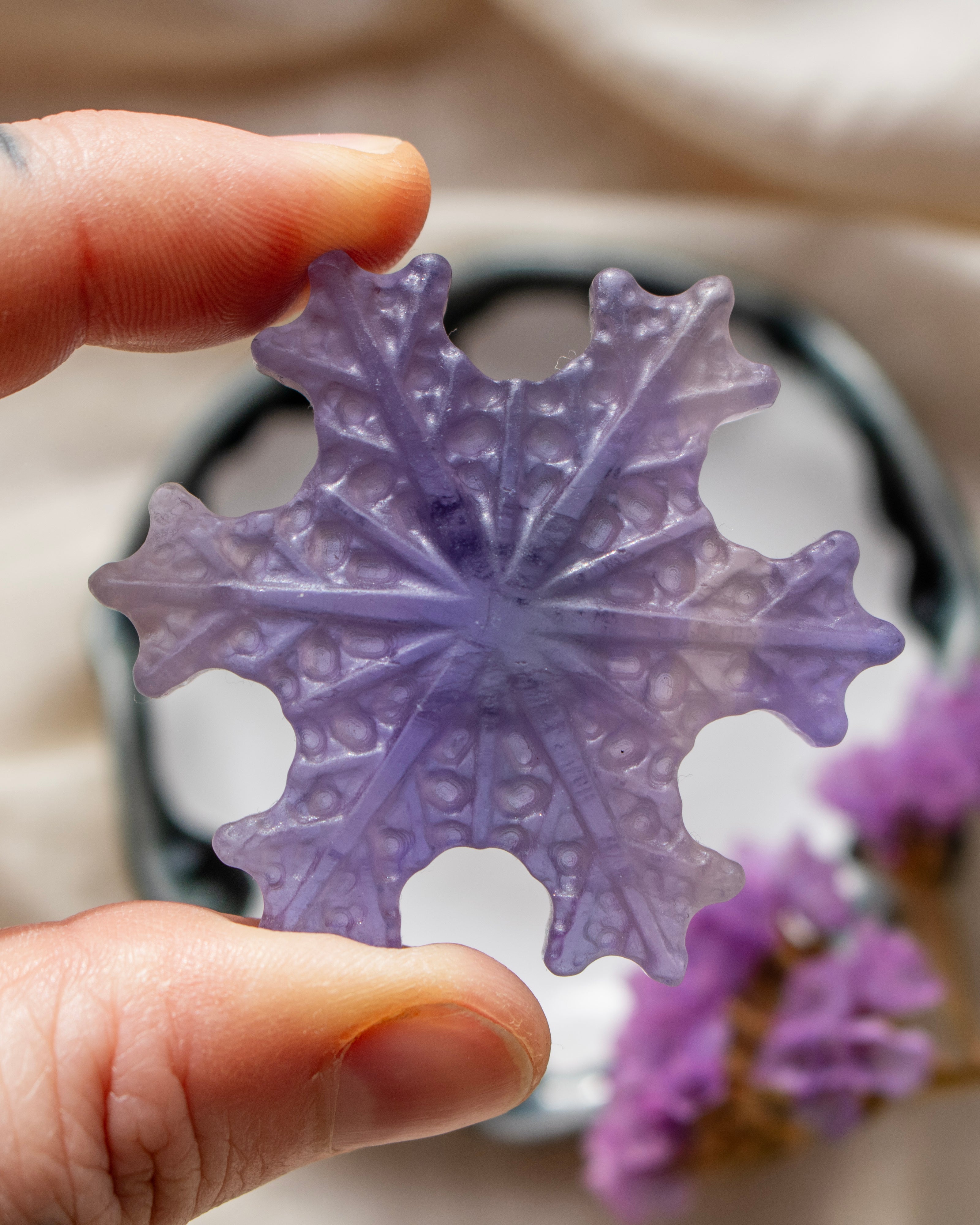 a purple snowflake being held with a blurred background