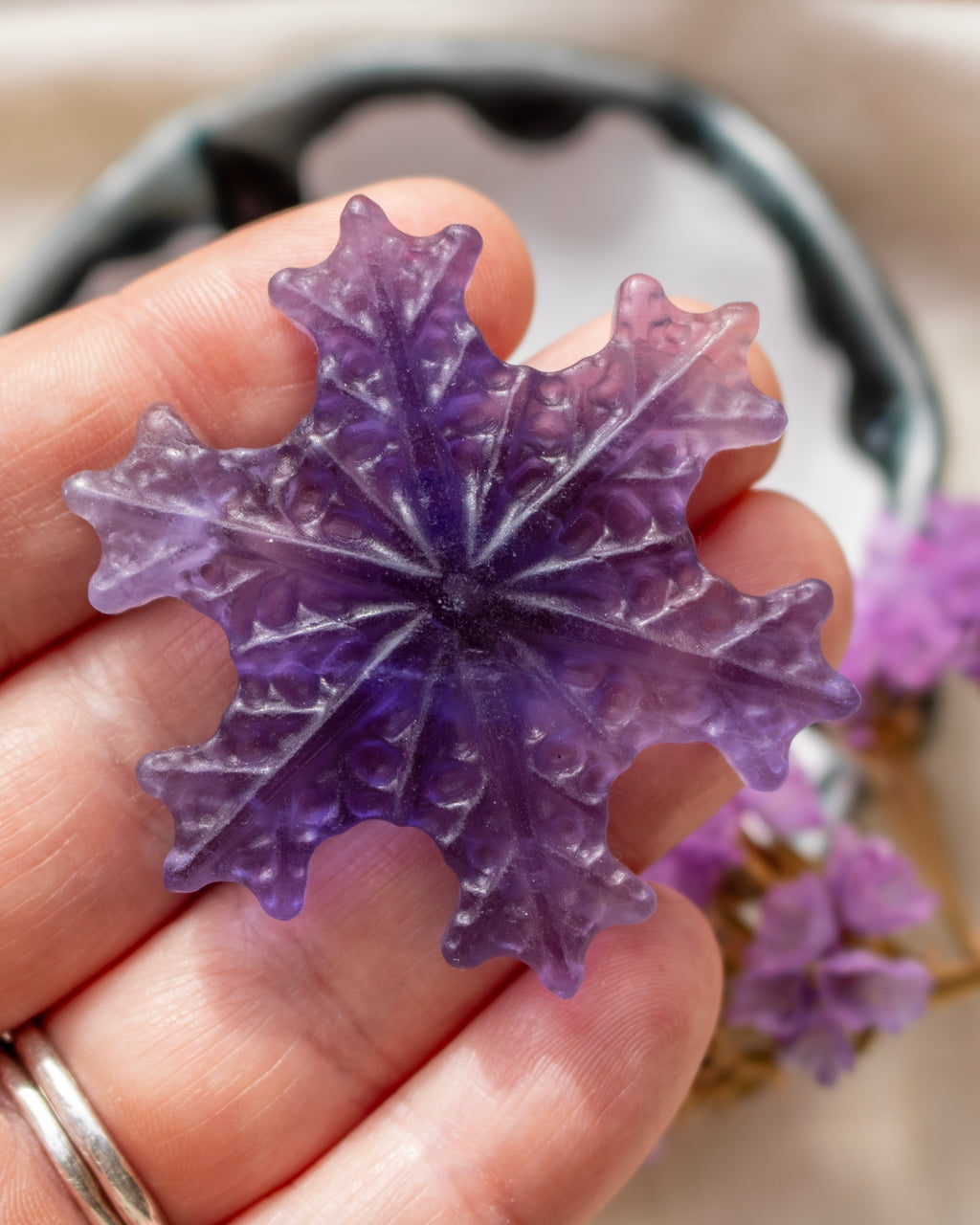 a purple snowflake being held with a blurred background