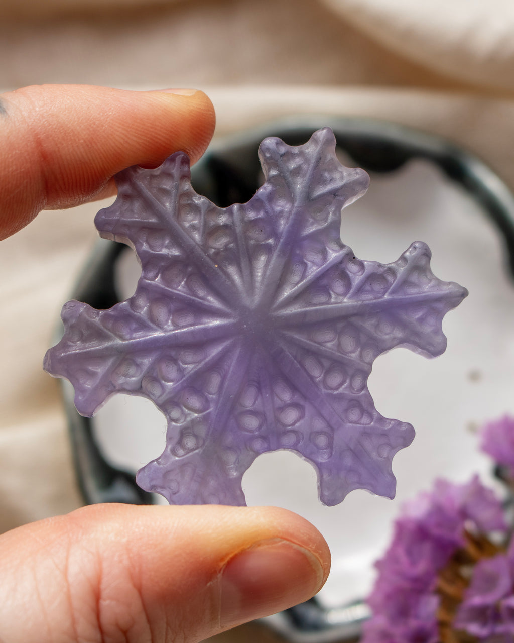 a purple snowflake being held with a blurred background