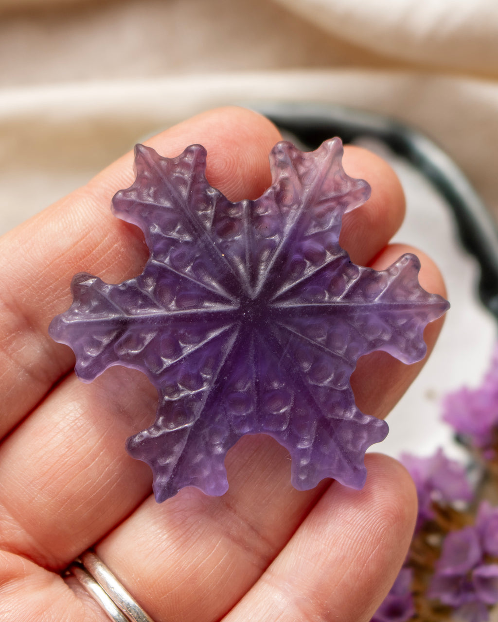 a purple snowflake being held with a blurred background