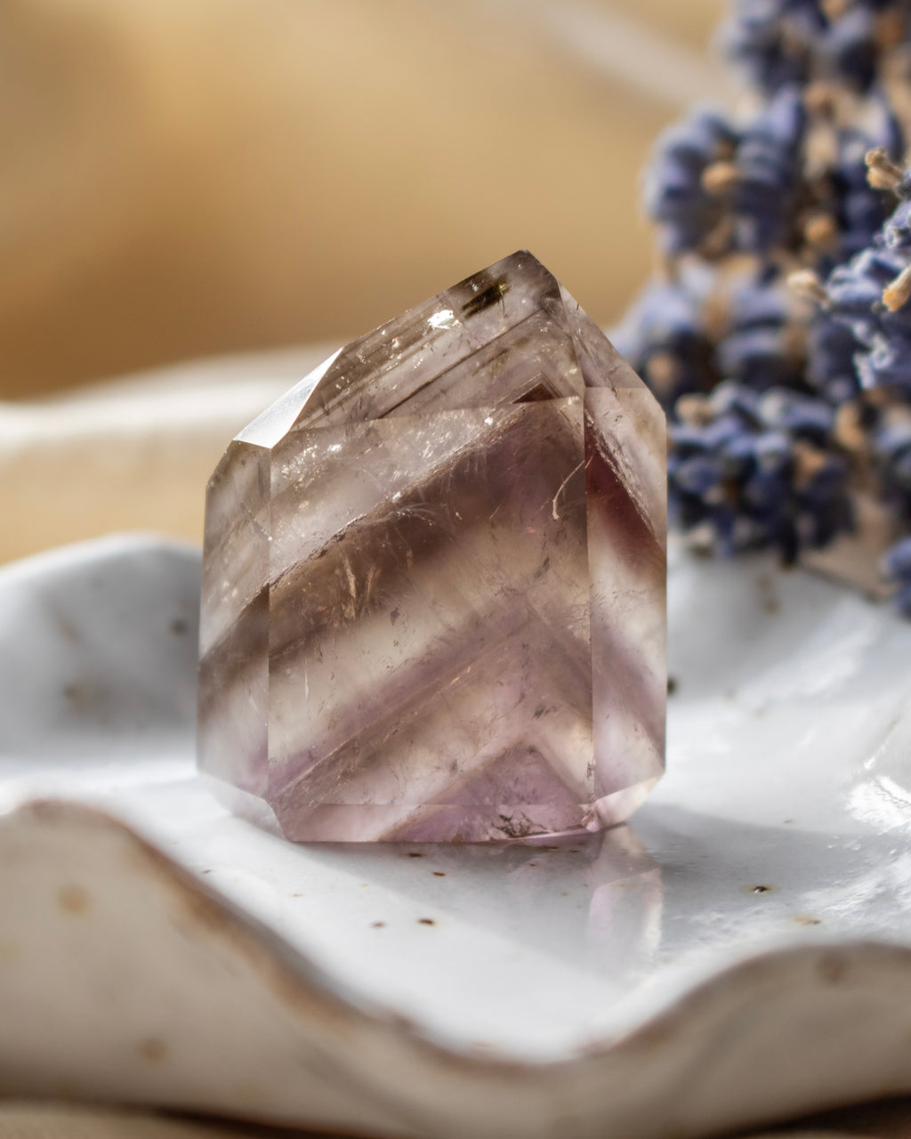 Crystal on a white surface with blurred lavender flowers in the background