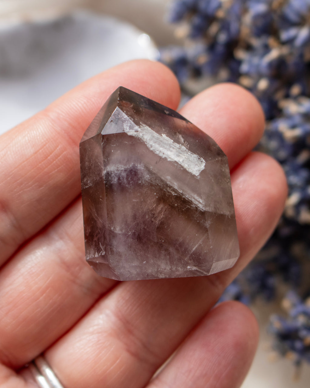 Hand holding a clear crystal with a blurred background