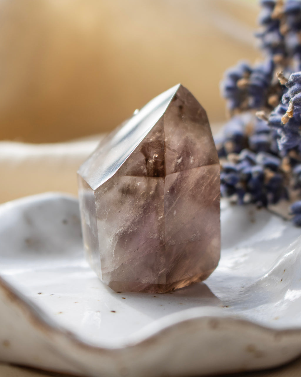 Smoky crystal on a white surface with blurred lavender flowers in the background