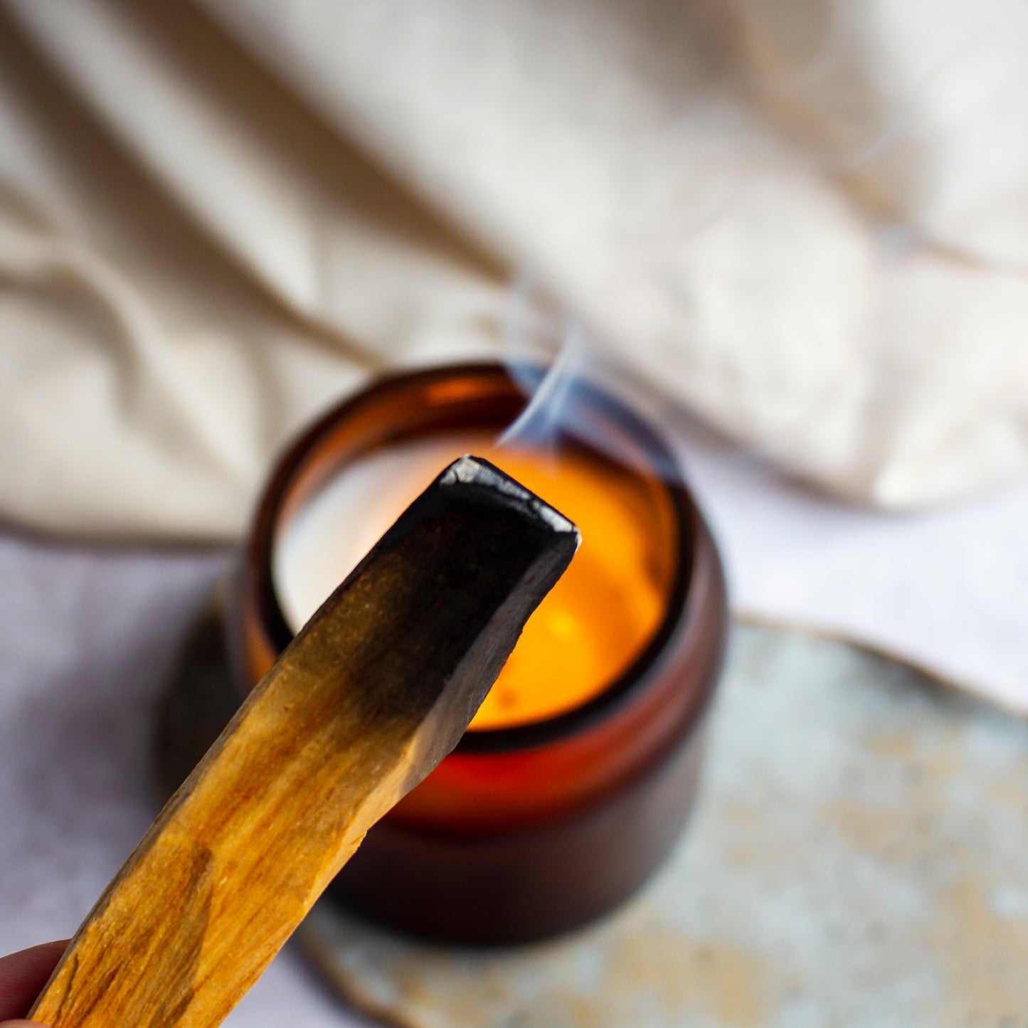 A smoldering Palo Santo stick releasing a trail of fragrant smoke.