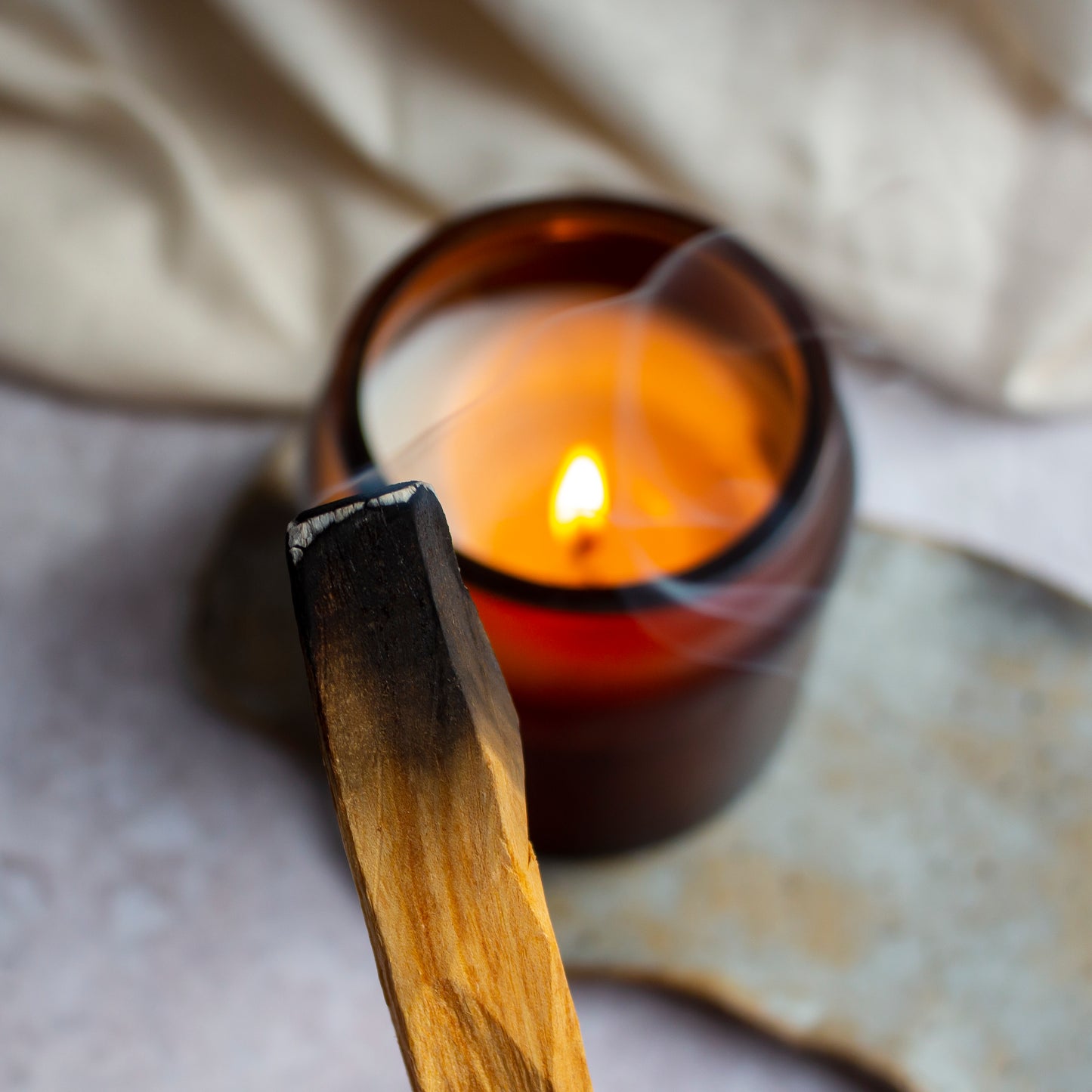 A smoldering Palo Santo stick releasing a trail of fragrant smoke.