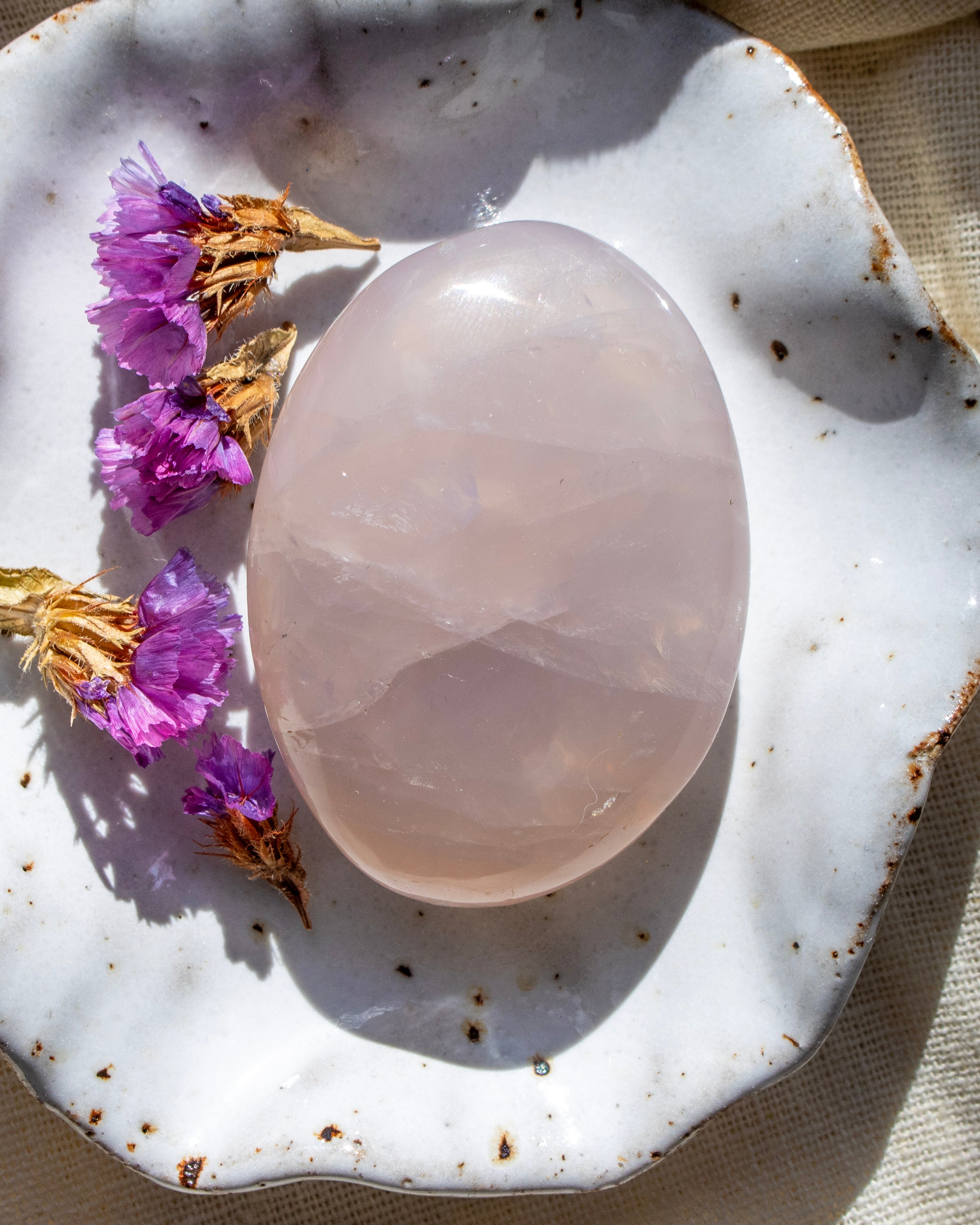 Pink stone on a textured white surface with purple flowers