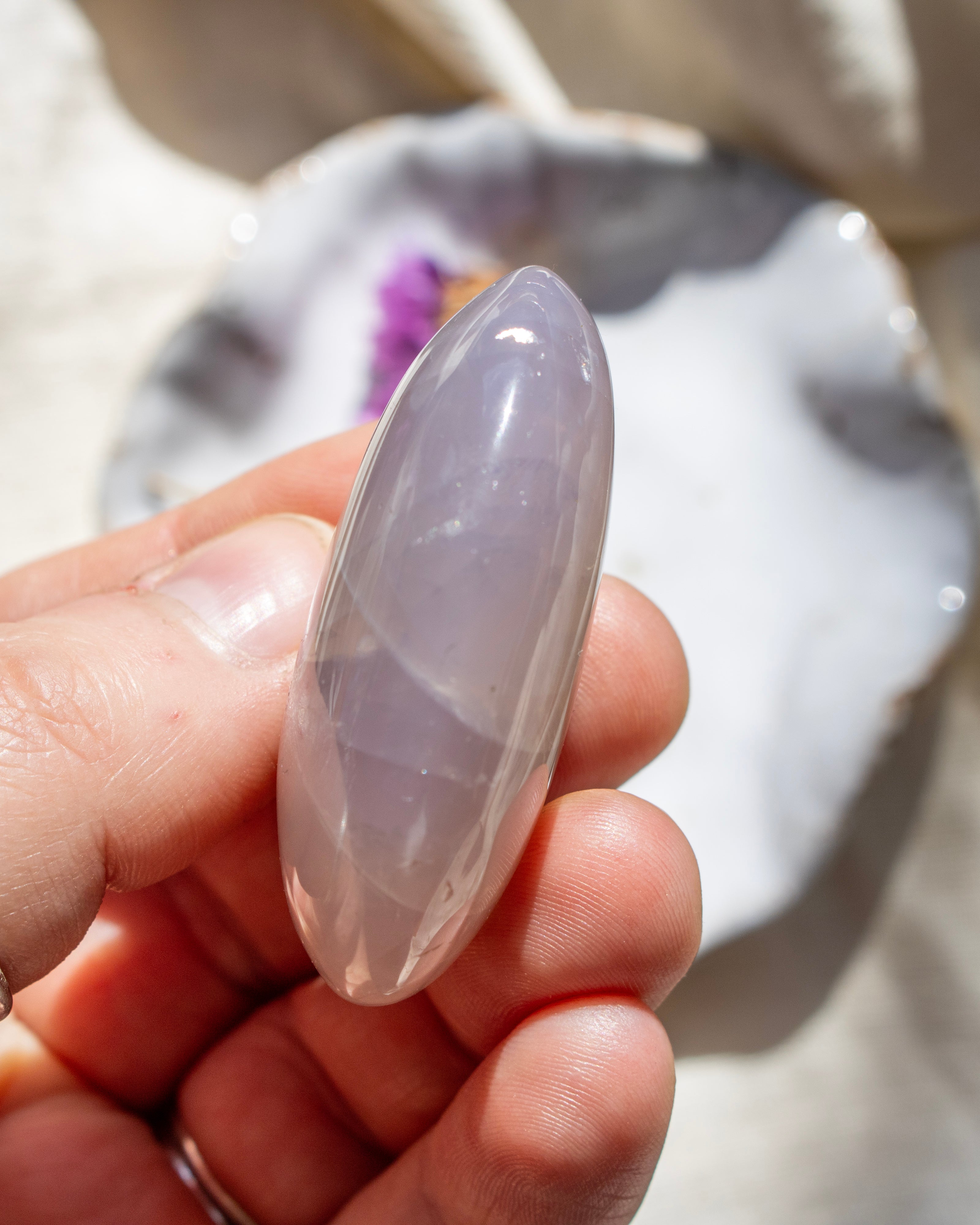 Hand holding a smooth, oval-shaped stone with a blurred natural background