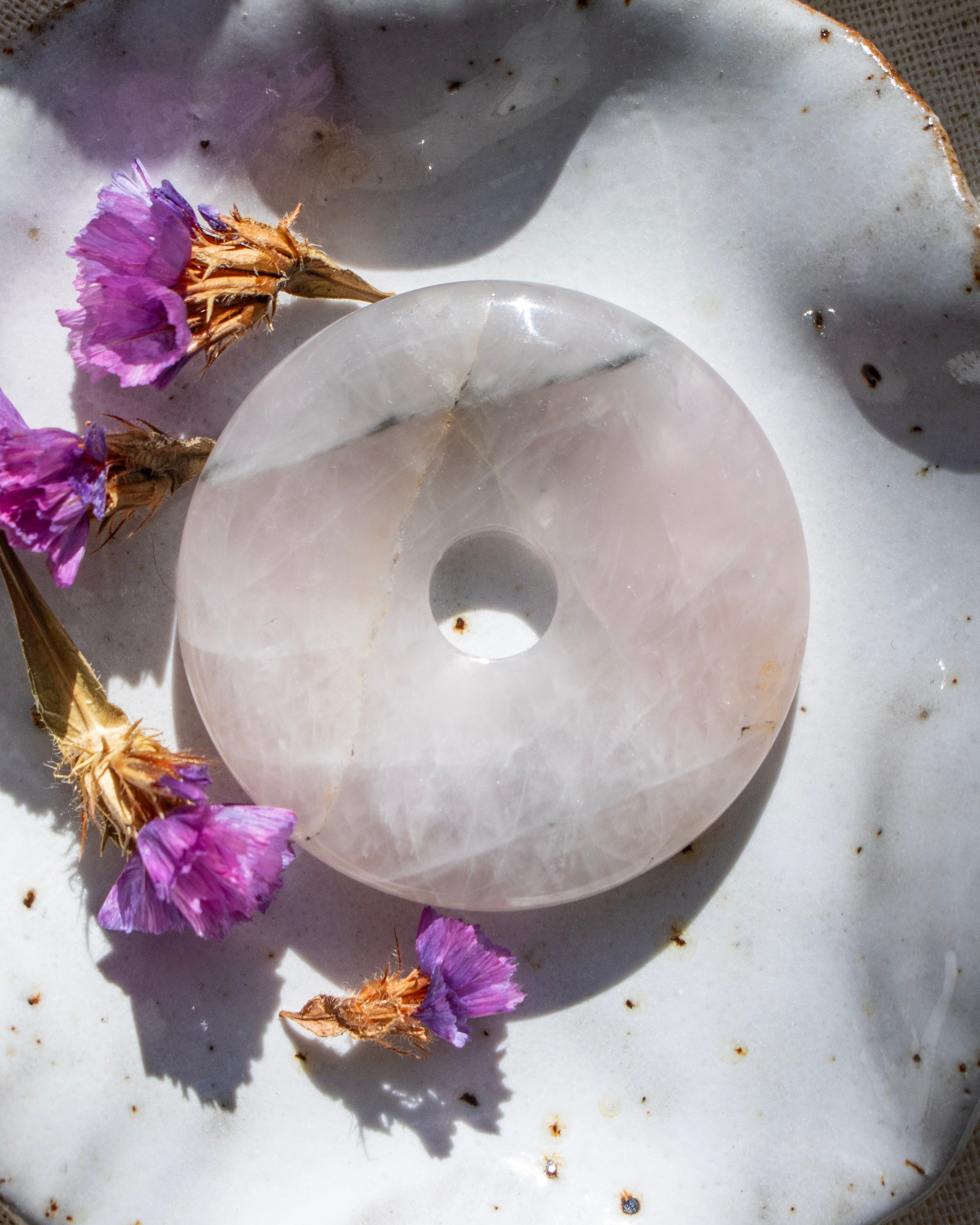 Crystal donut on a textured surface with purple flowers