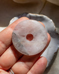 Person holding a stone disc with a central hole against a neutral background