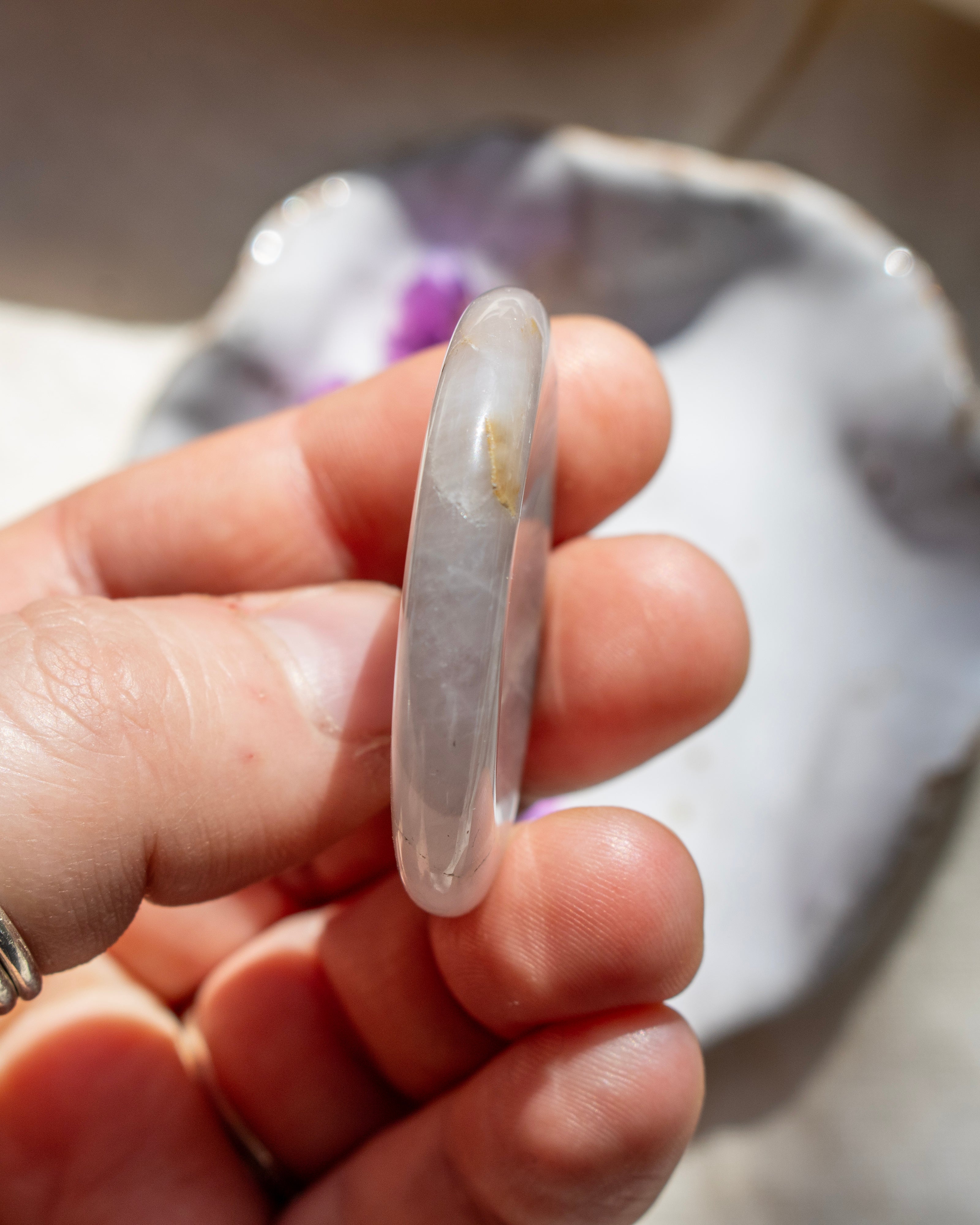 Hand holding a clear stone with a blurred background
