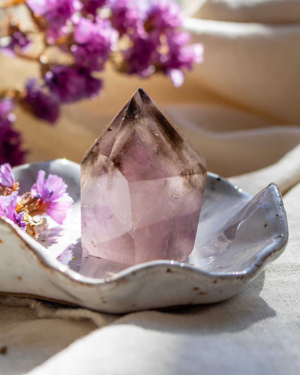 Crystal on a ceramic dish with purple flowers in the background