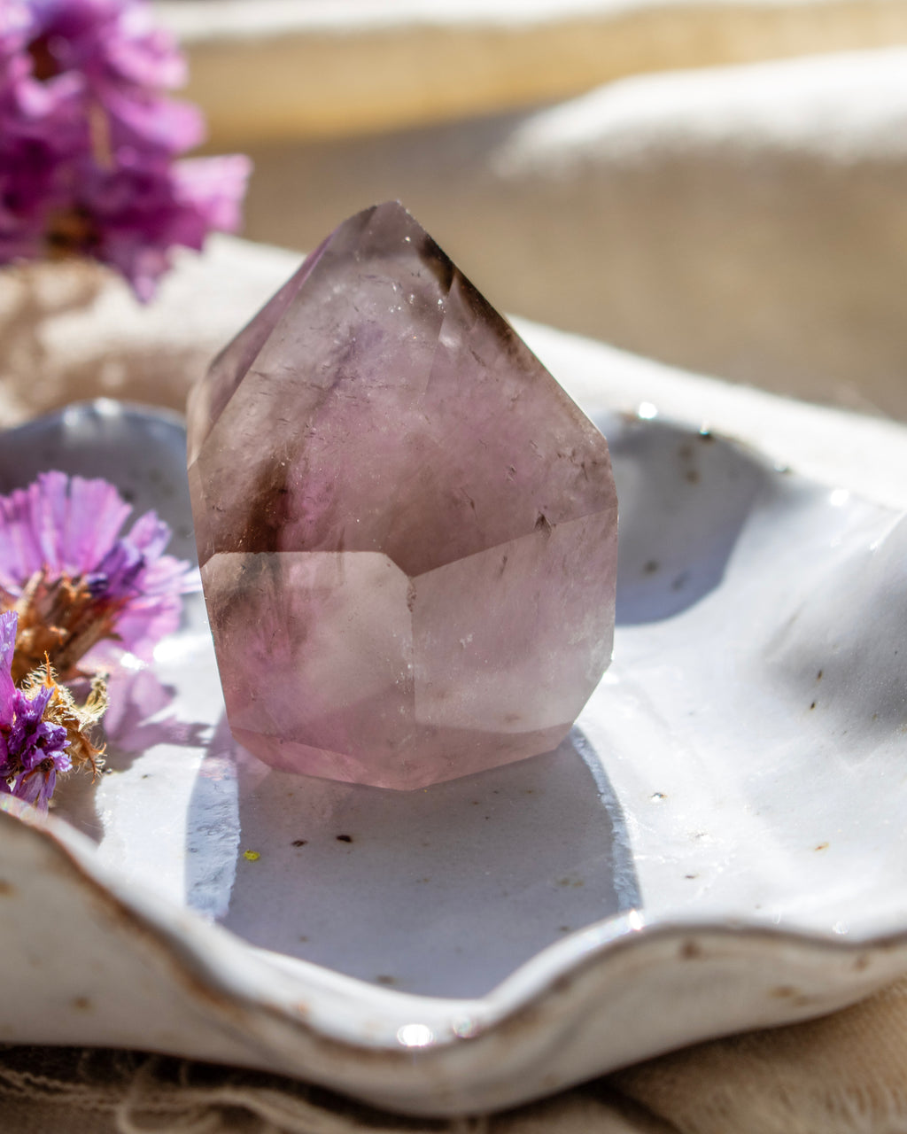 Pink crystal on a white ceramic dish with purple flowers