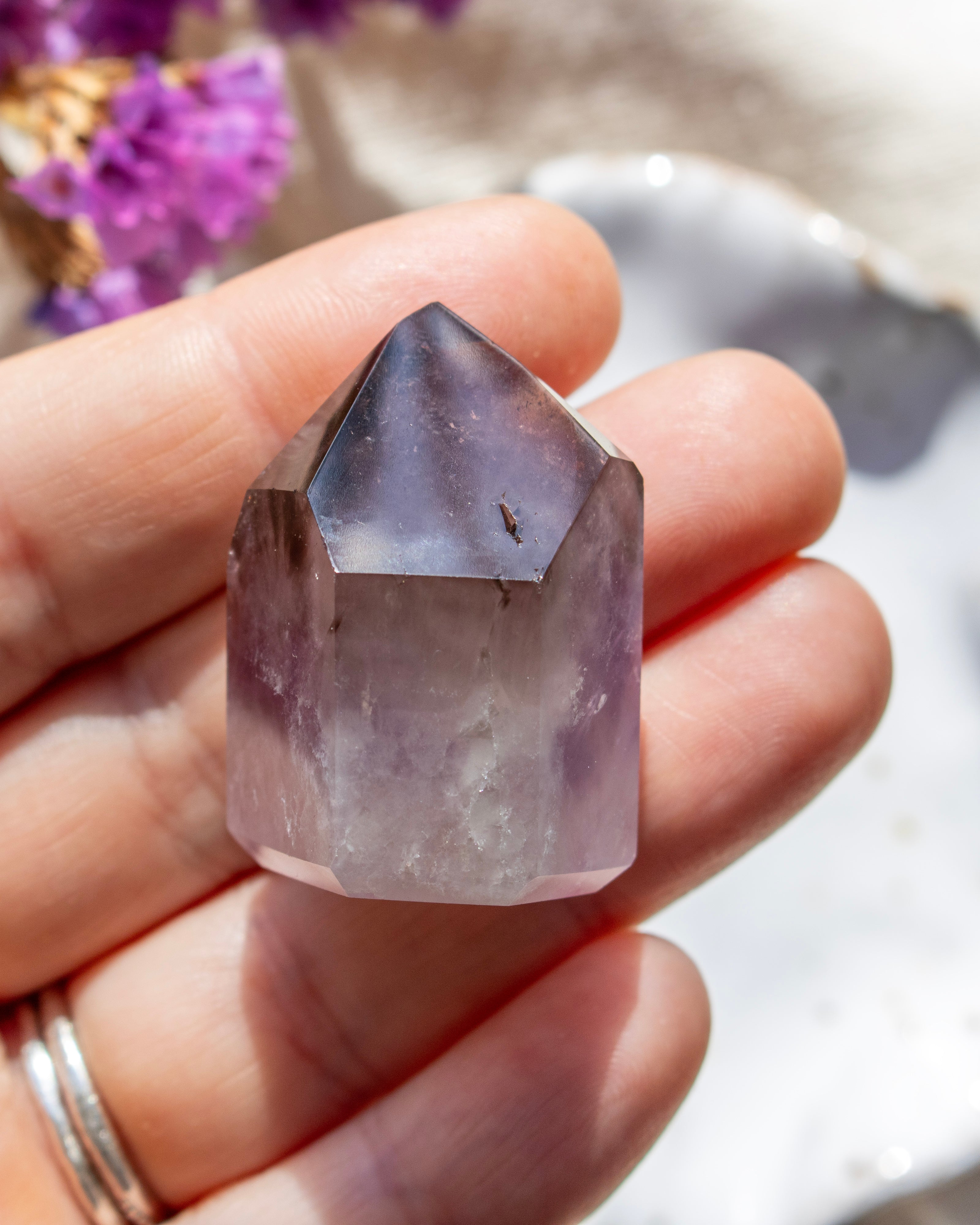 Hand holding a clear crystal with a blurred natural background