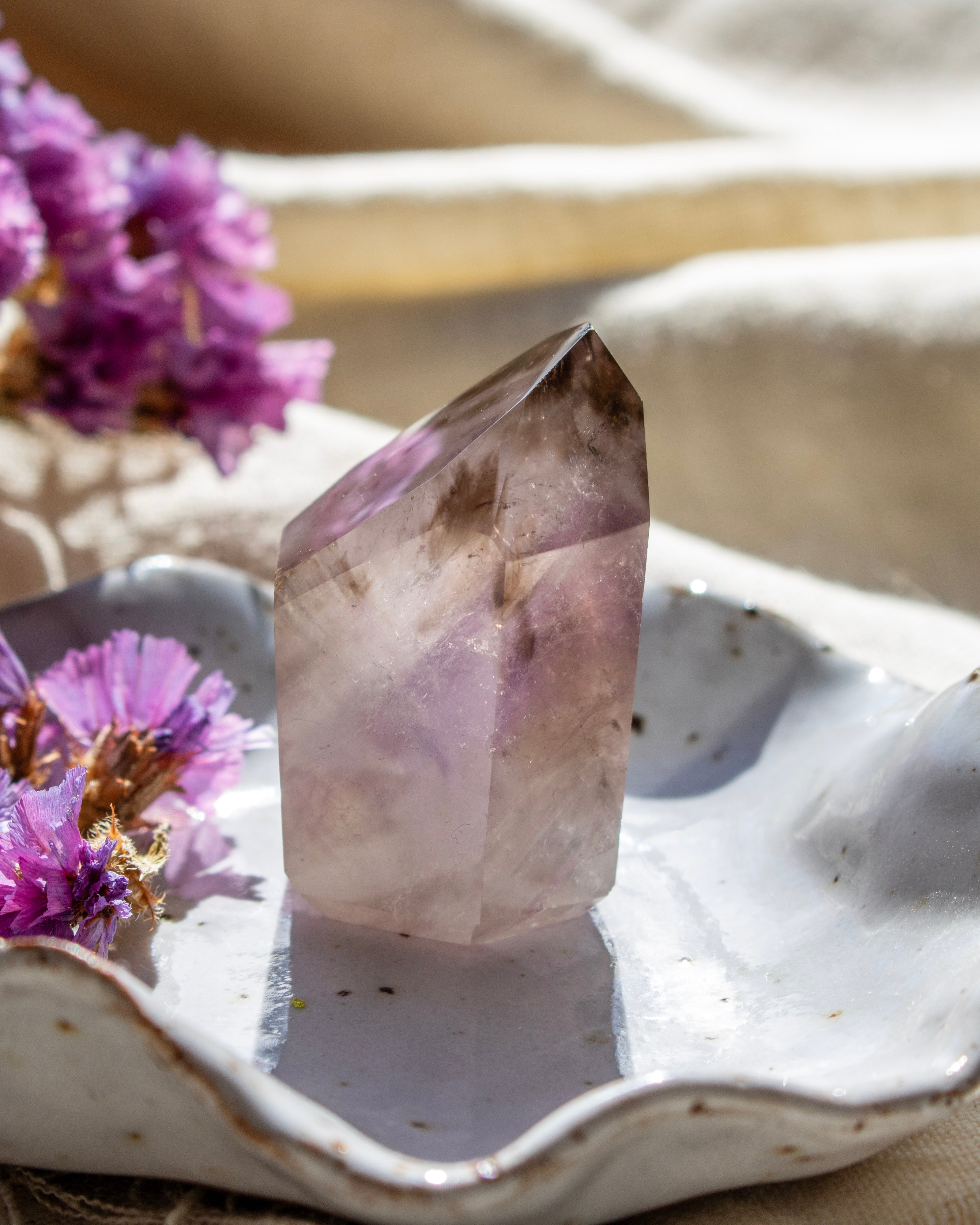 Crystal on a white dish with purple flowers in the background