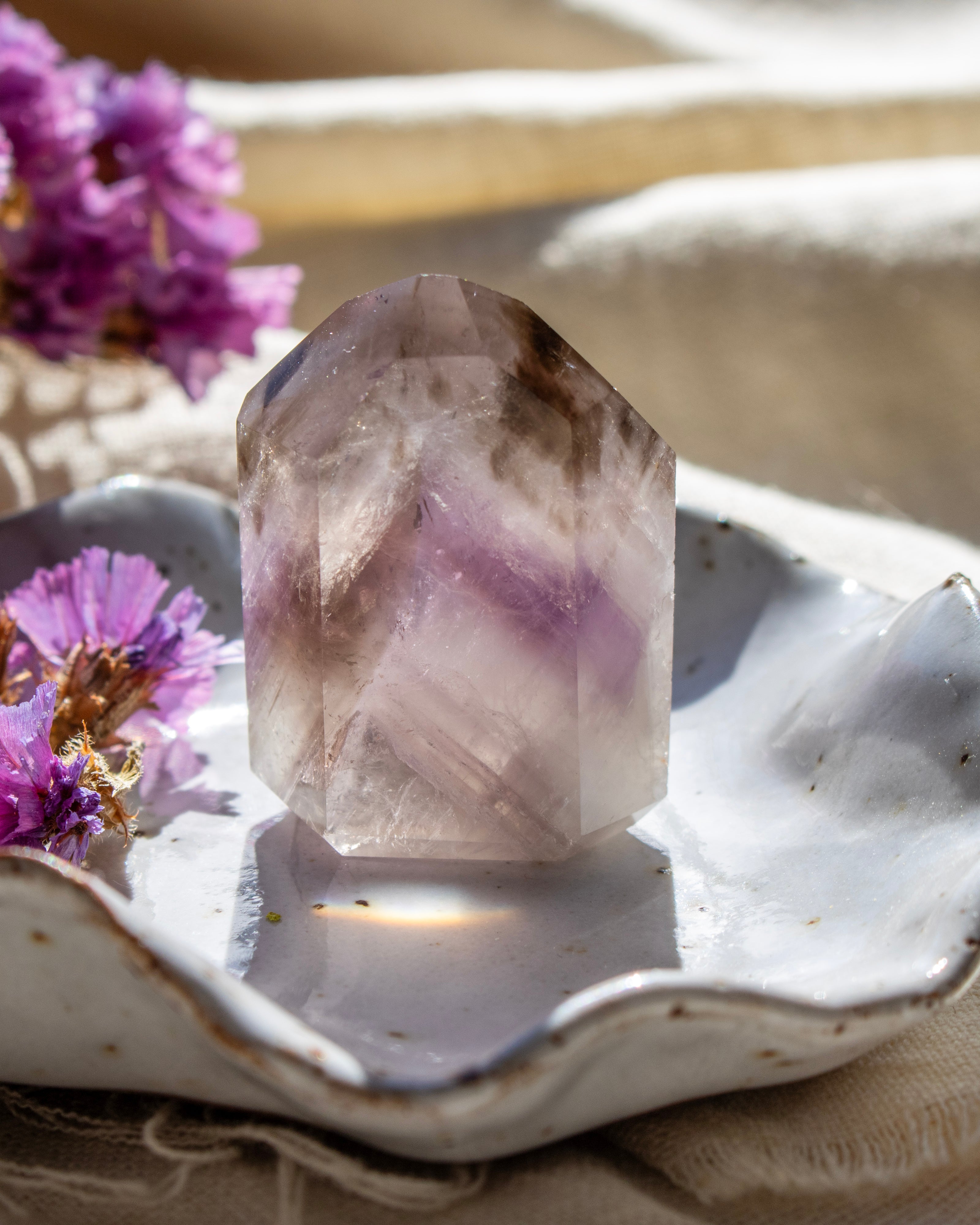 Crystal on a decorative plate with purple flowers in the background
