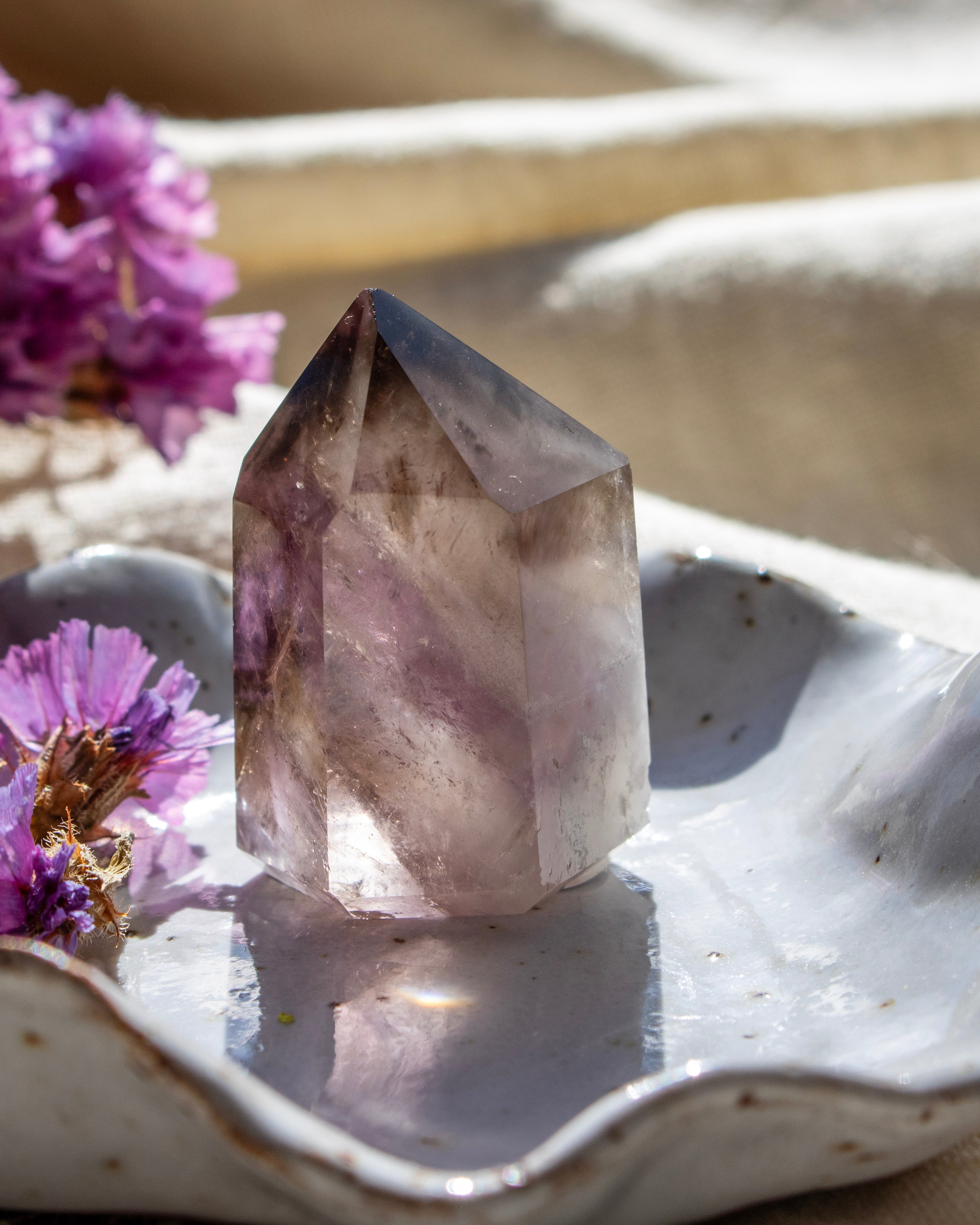 Amethyst crystal on a white ceramic dish with purple flowers