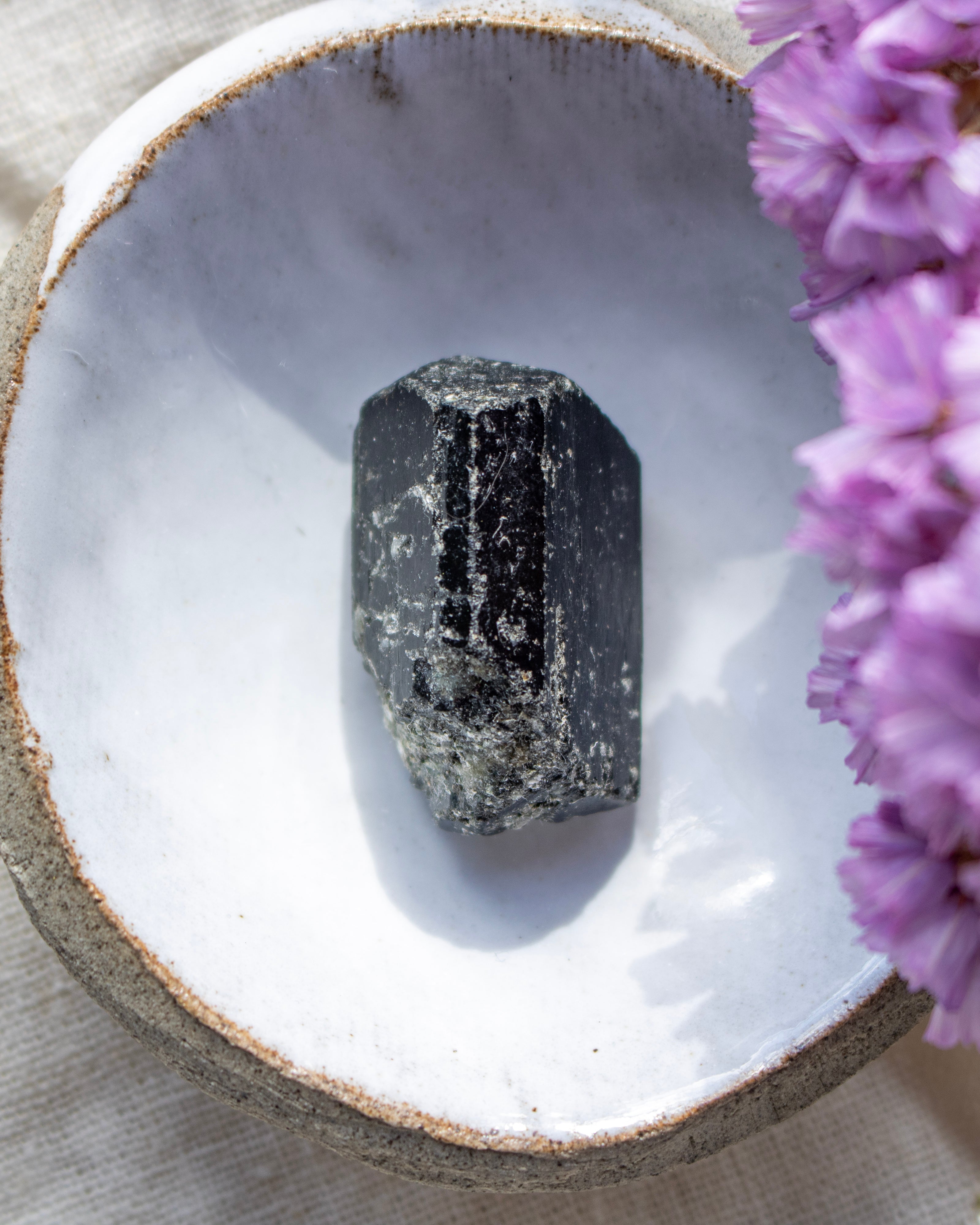 Mineral crystal on a white stone surface with purple flowers