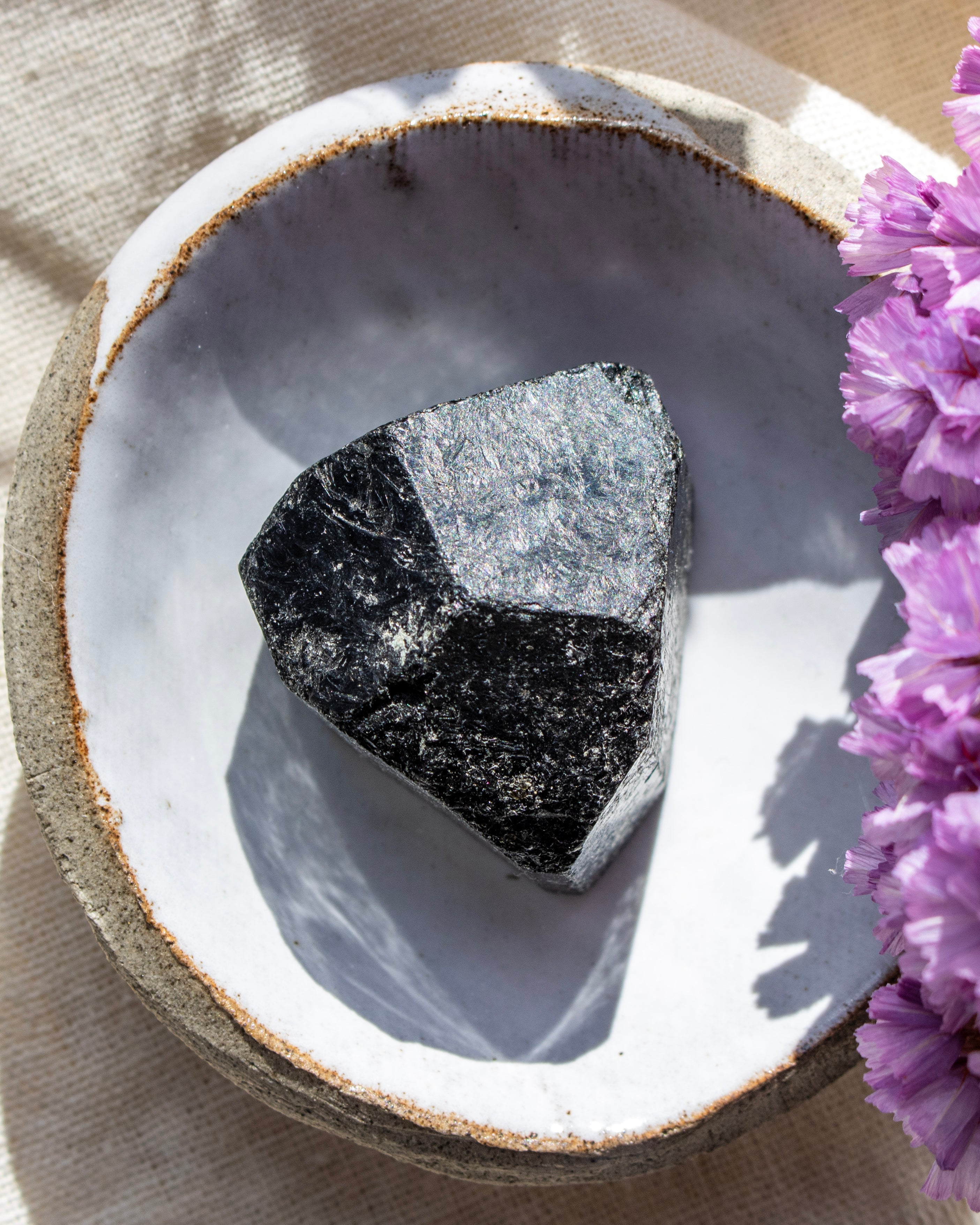Mineral specimen on a decorative stone surface with purple flowers