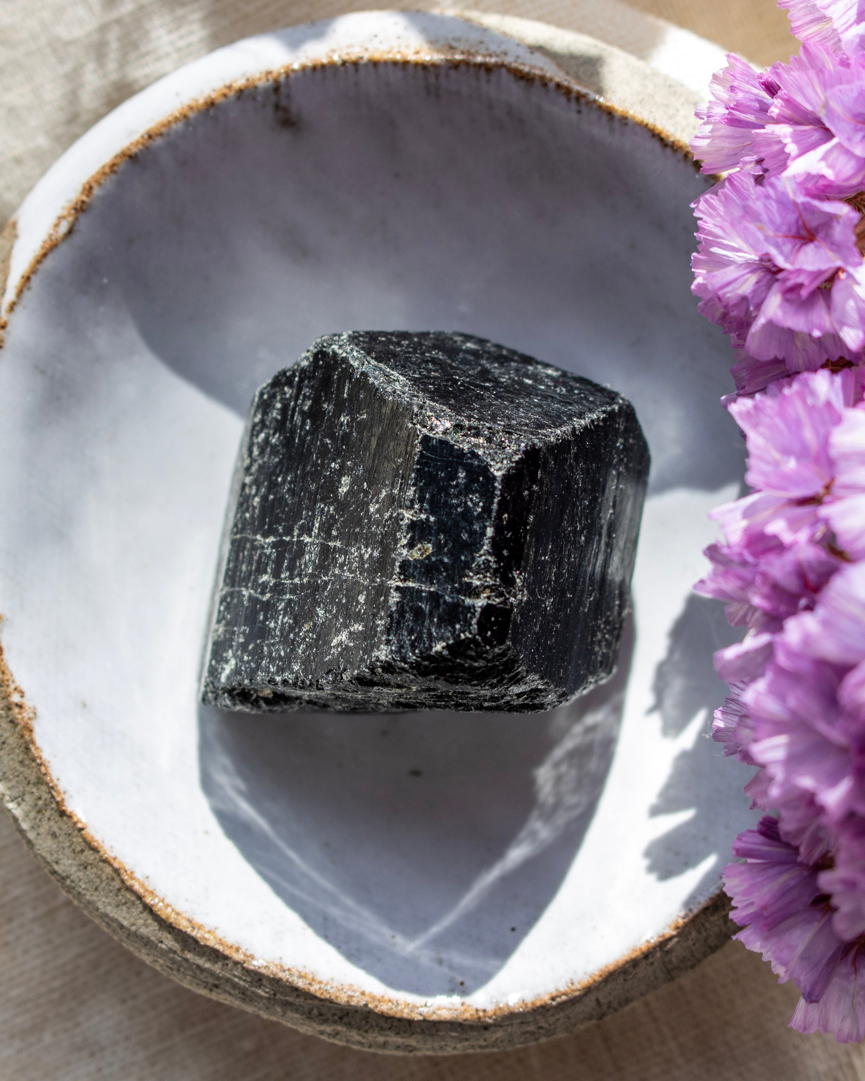 Black crystal on a white stone surface with pink flowers
